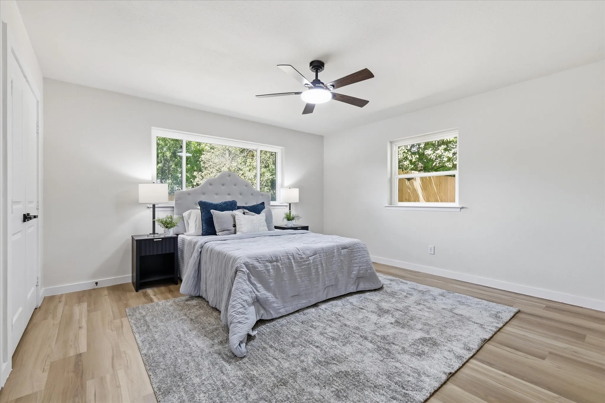 Spacious room featuring wood-finish flooring, light-toned walls, and a contemporary ceiling fan with integrated lighting