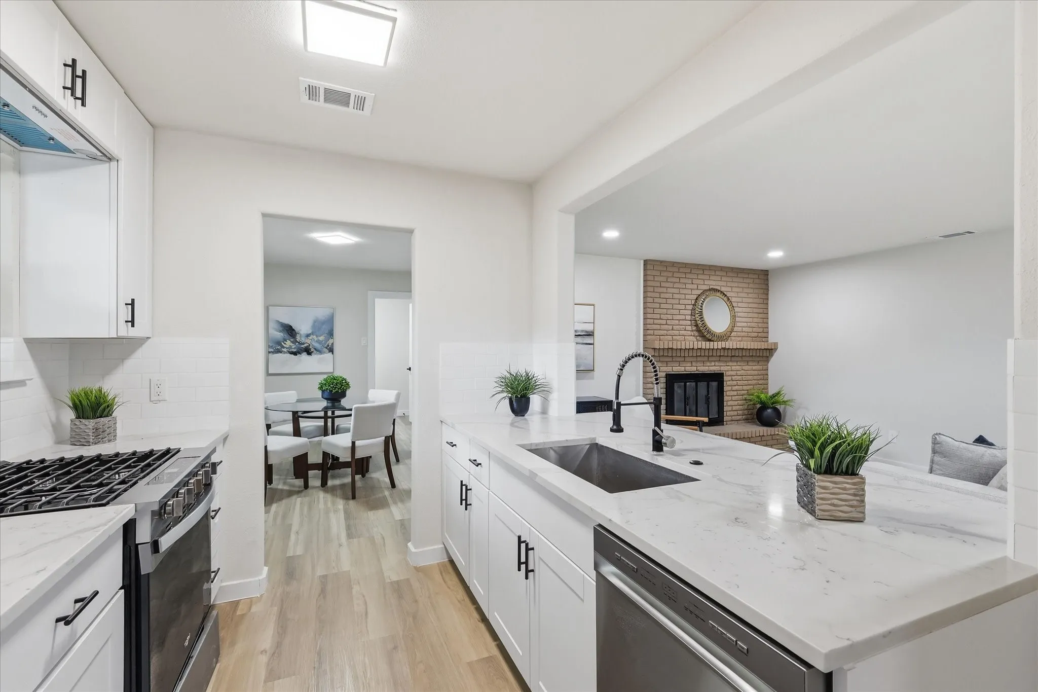 Modern kitchen featuring white shaker cabinetry, light-toned countertops, subway tile backsplash, and a stainless steel appliance suite