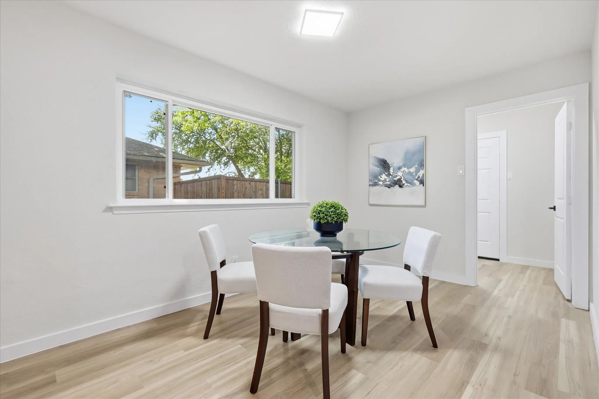 Dining area featuring wood-finish flooring, a large window with white trim, and a recessed ceiling light fixture