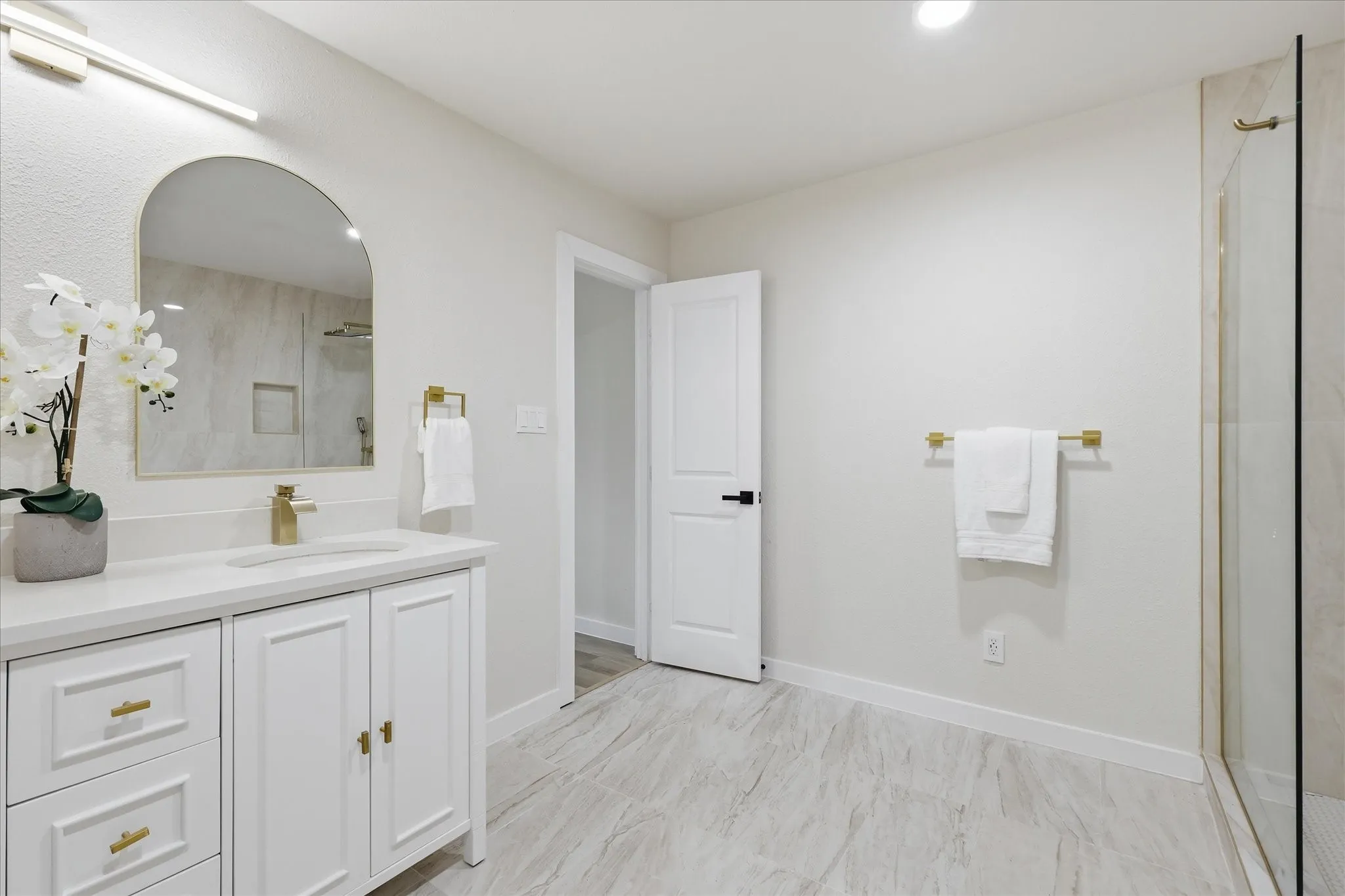 Bathroom featuring a white vanity with gold hardware, a rectangular undermount sink, and a white countertop