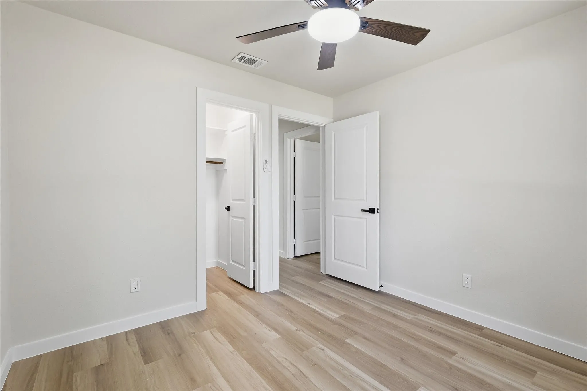 Room featuring wood-finish flooring, white baseboards, and a contemporary ceiling fan with integrated lighting