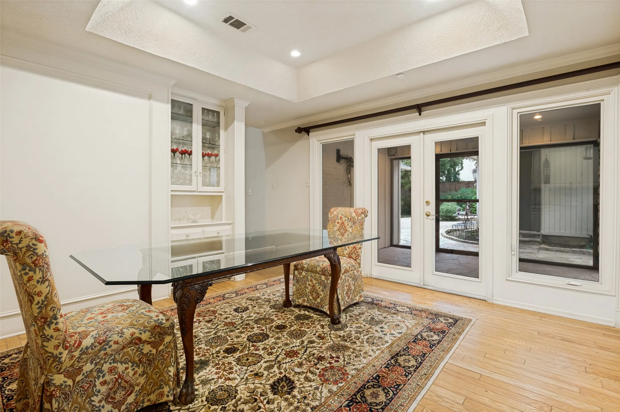 Room featuring a built-in display cabinet with glass-front doors, recessed lighting, and wood-finish flooring