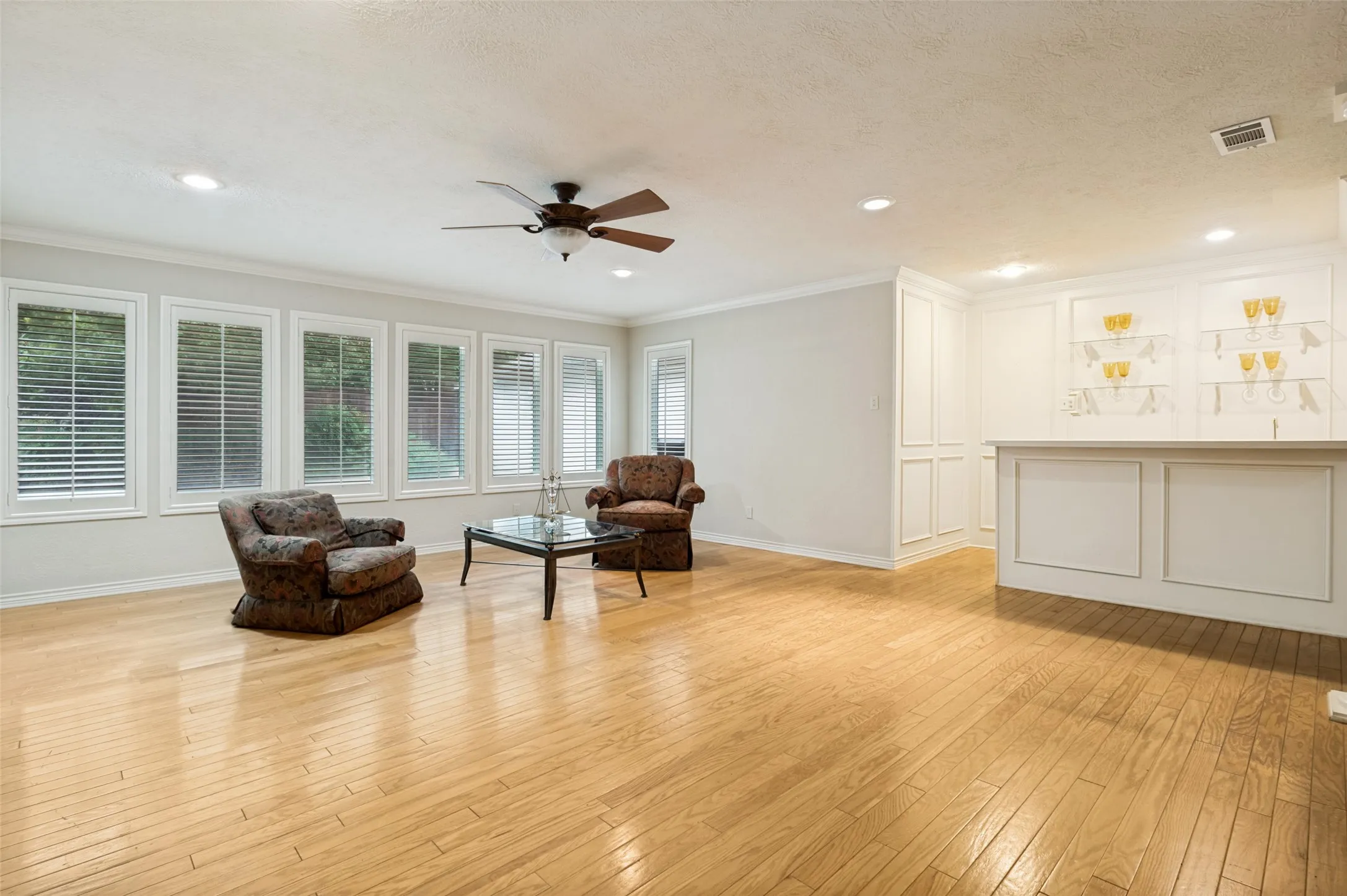 Spacious room featuring wood-finish flooring, recessed lighting, and a ceiling fan