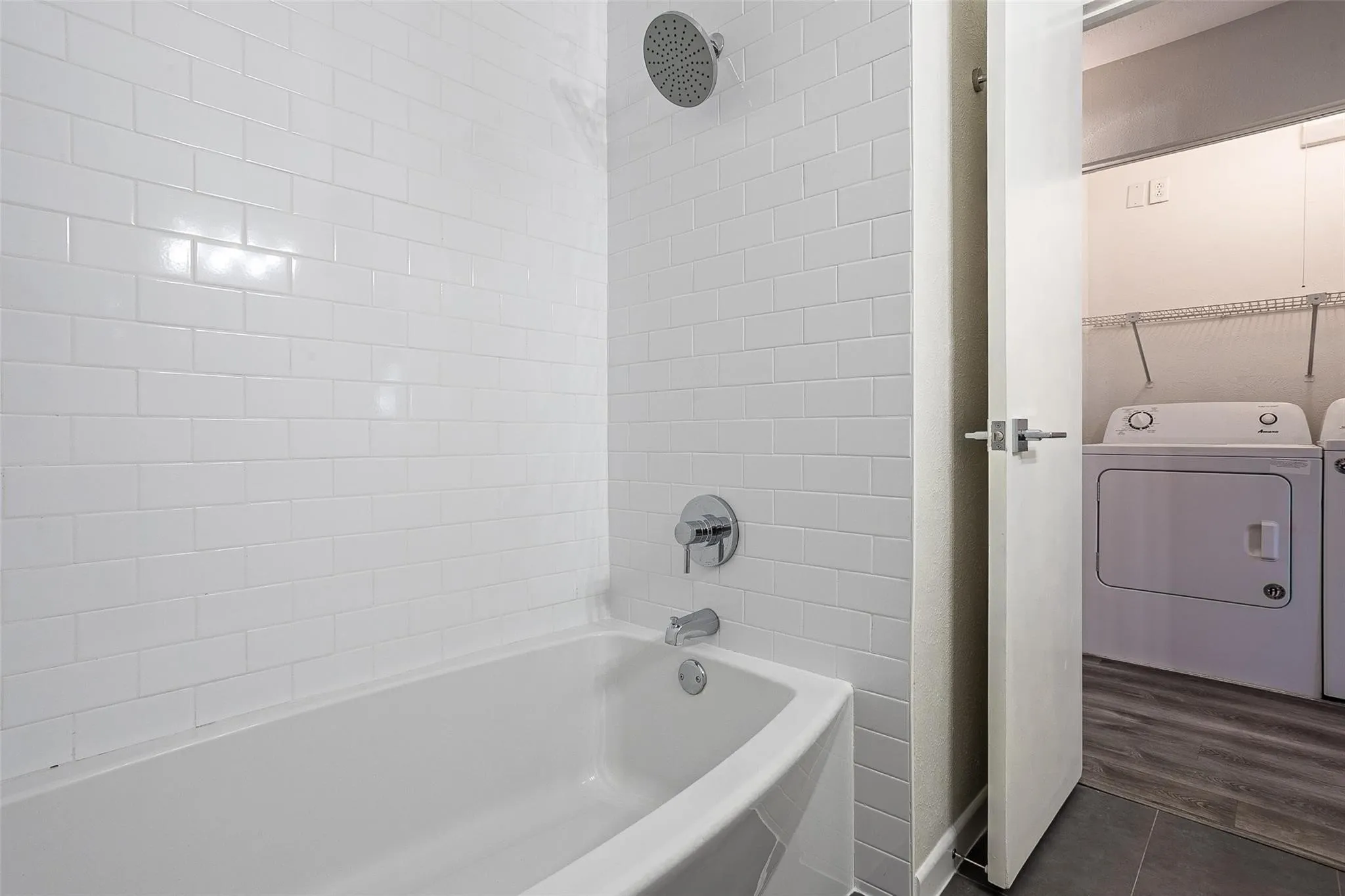 Bathtub with white subway tile surround, chrome fixtures, and rain shower head