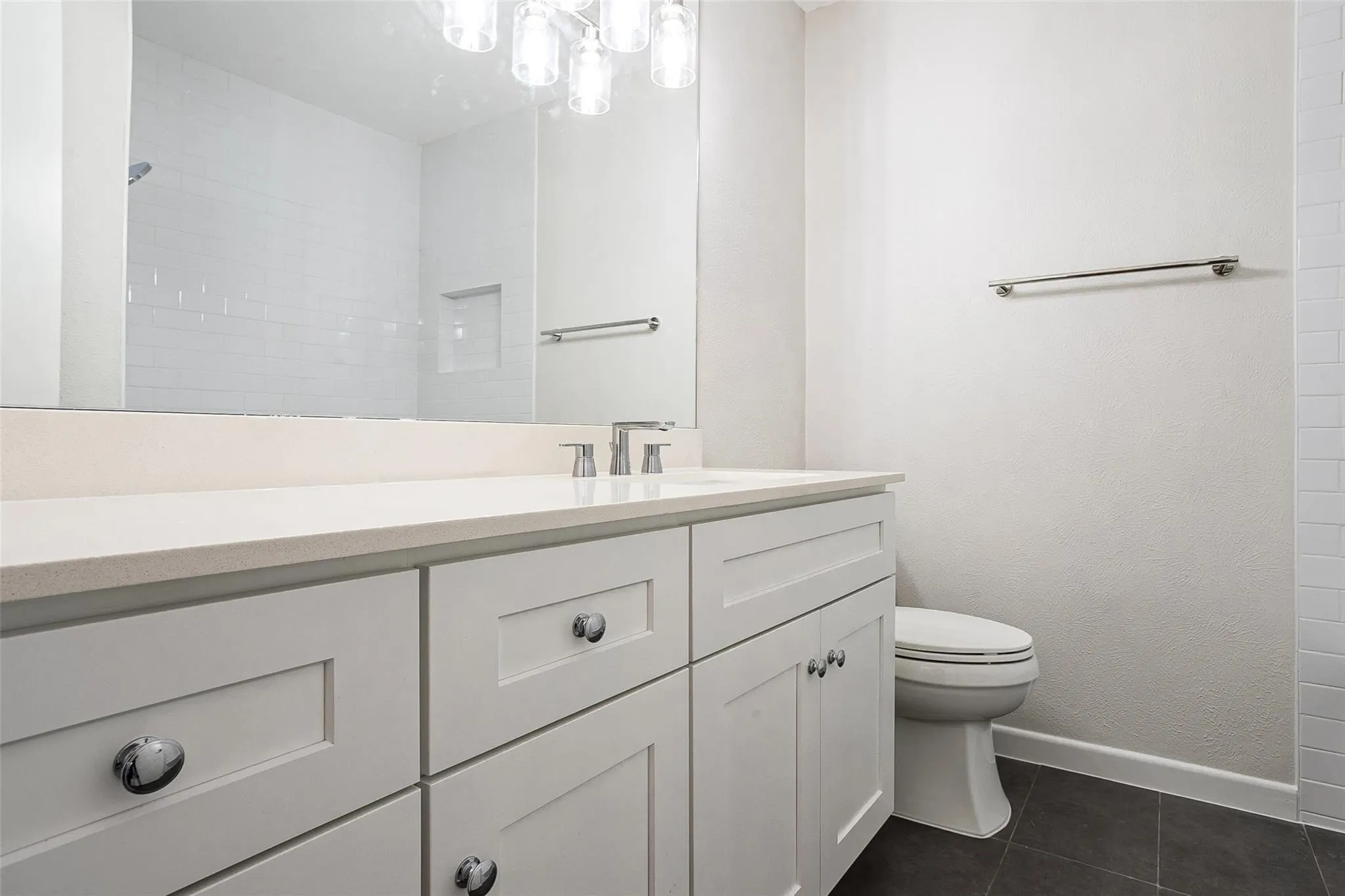 White shaker-style vanity with chrome hardware, topped with a light-colored countertop