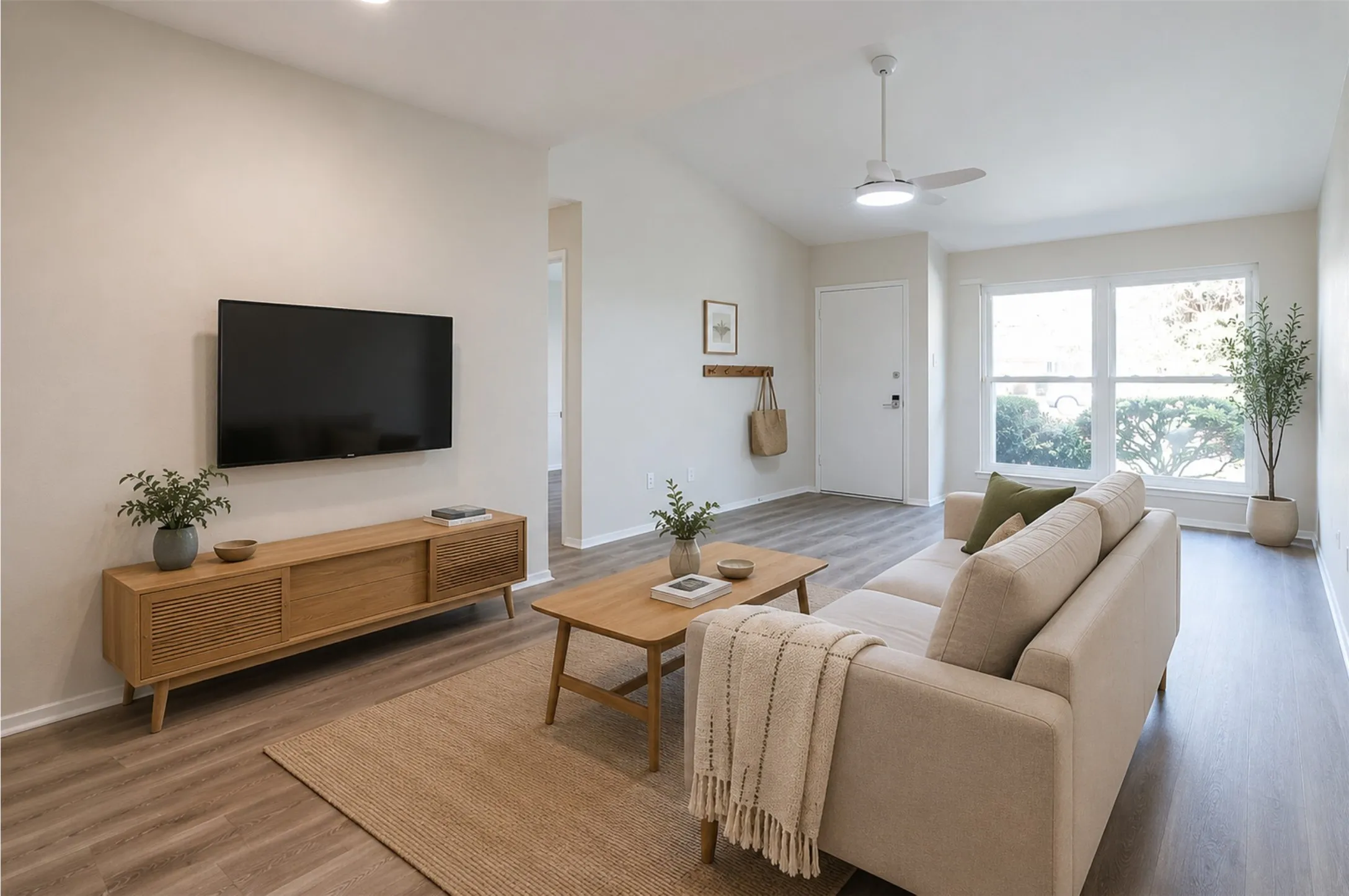 Spacious living area featuring vaulted ceilings, wood-finish flooring, and ample natural light from large windows
