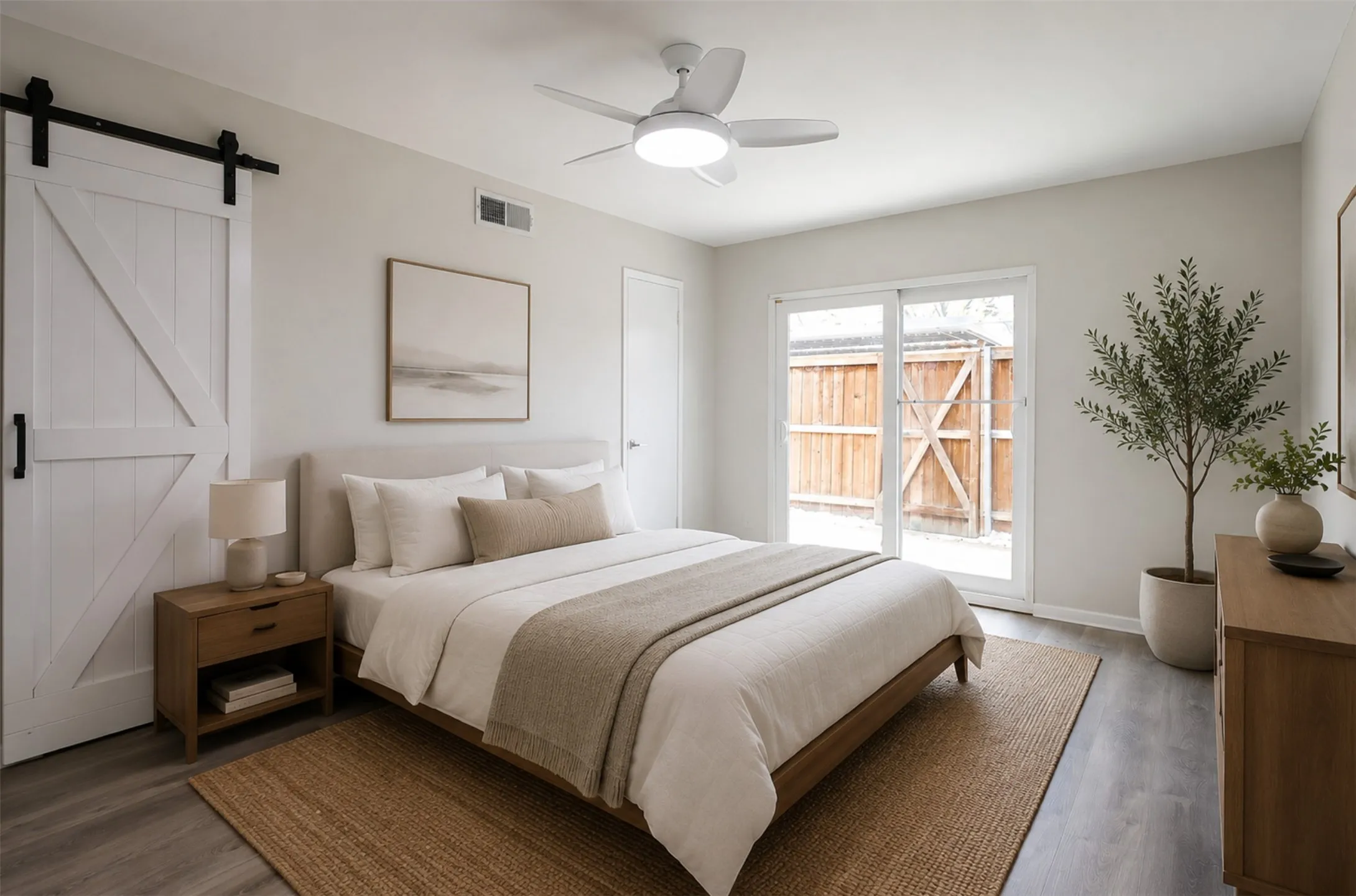 Bedroom featuring wood-finish flooring, a contemporary ceiling fan with integrated lighting, and a white barn door