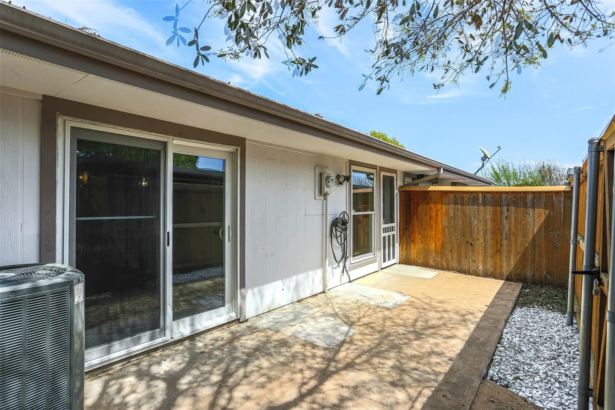 Private outdoor patio featuring a sliding glass door, an additional exterior door, and a full wood privacy fence