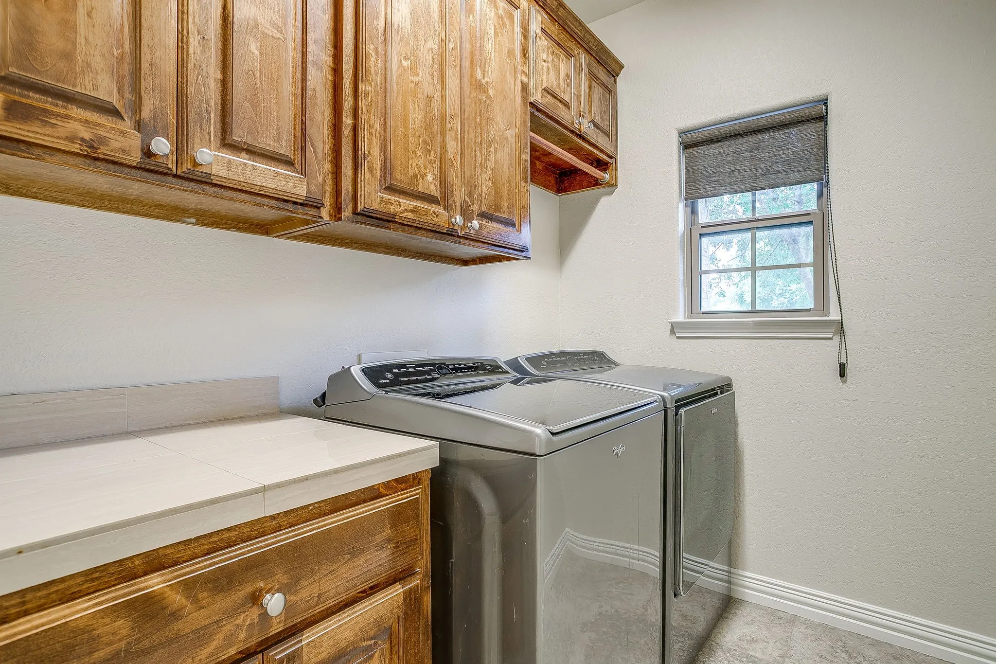 Large laundry room with extra cabinet space and tile folding counter top.