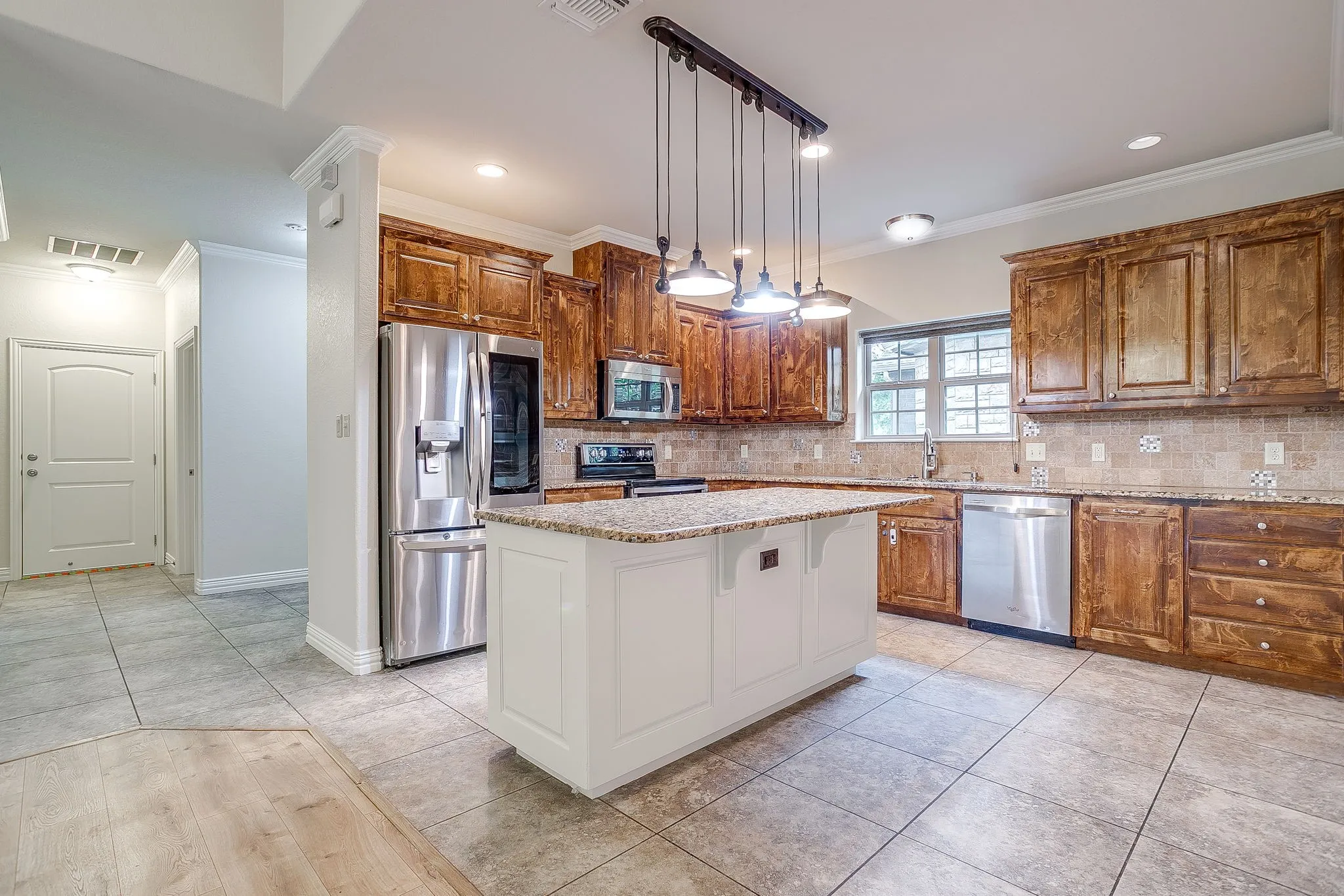 Kitchen with large tile floors, beautiful alder wood cabinbets, all granite counters, stainless appliances and sink. Fridge will remain with solid offer. Custom light over island with can lights in ceiling.