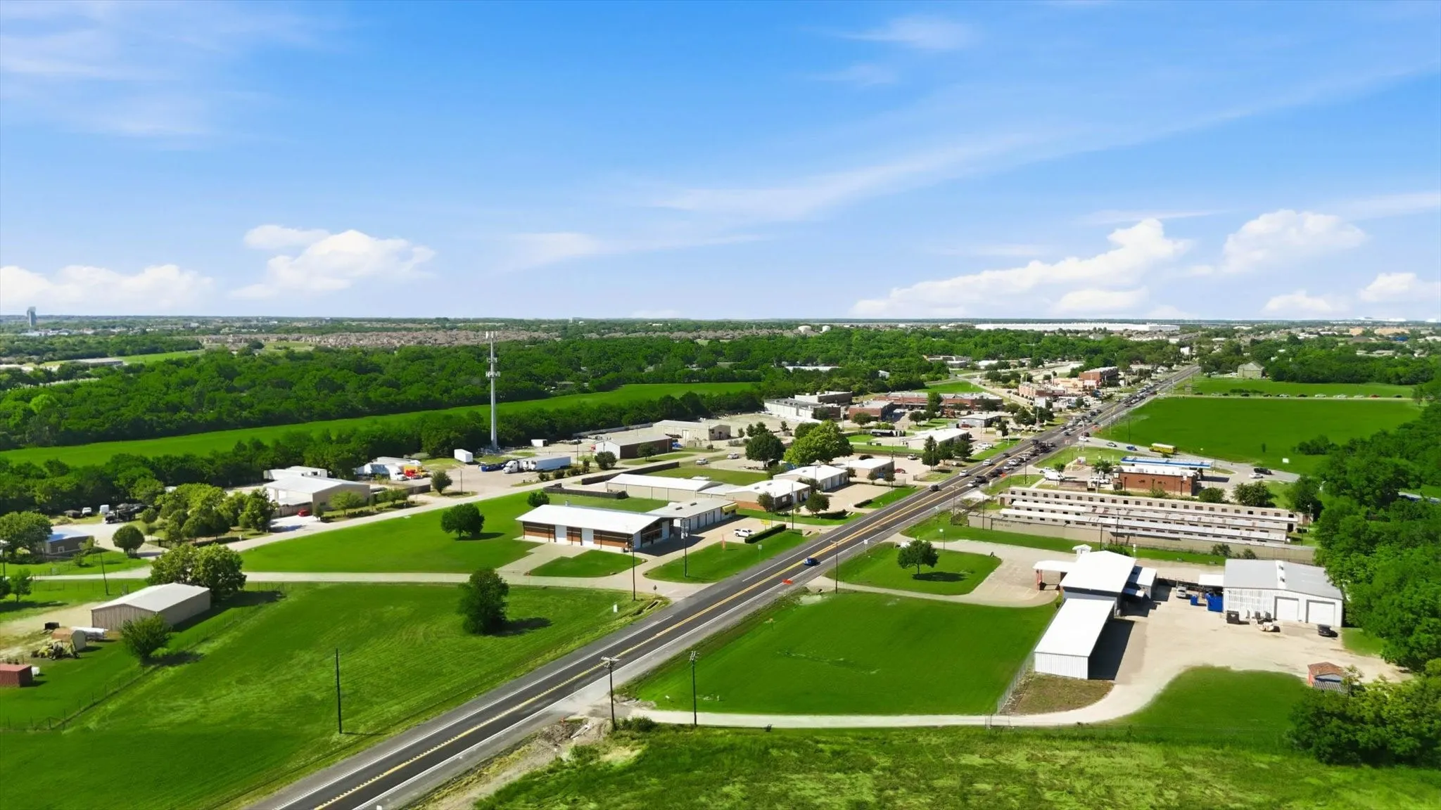 Expansive aerial capturing a commercial district with a prominent roadway and railway line
