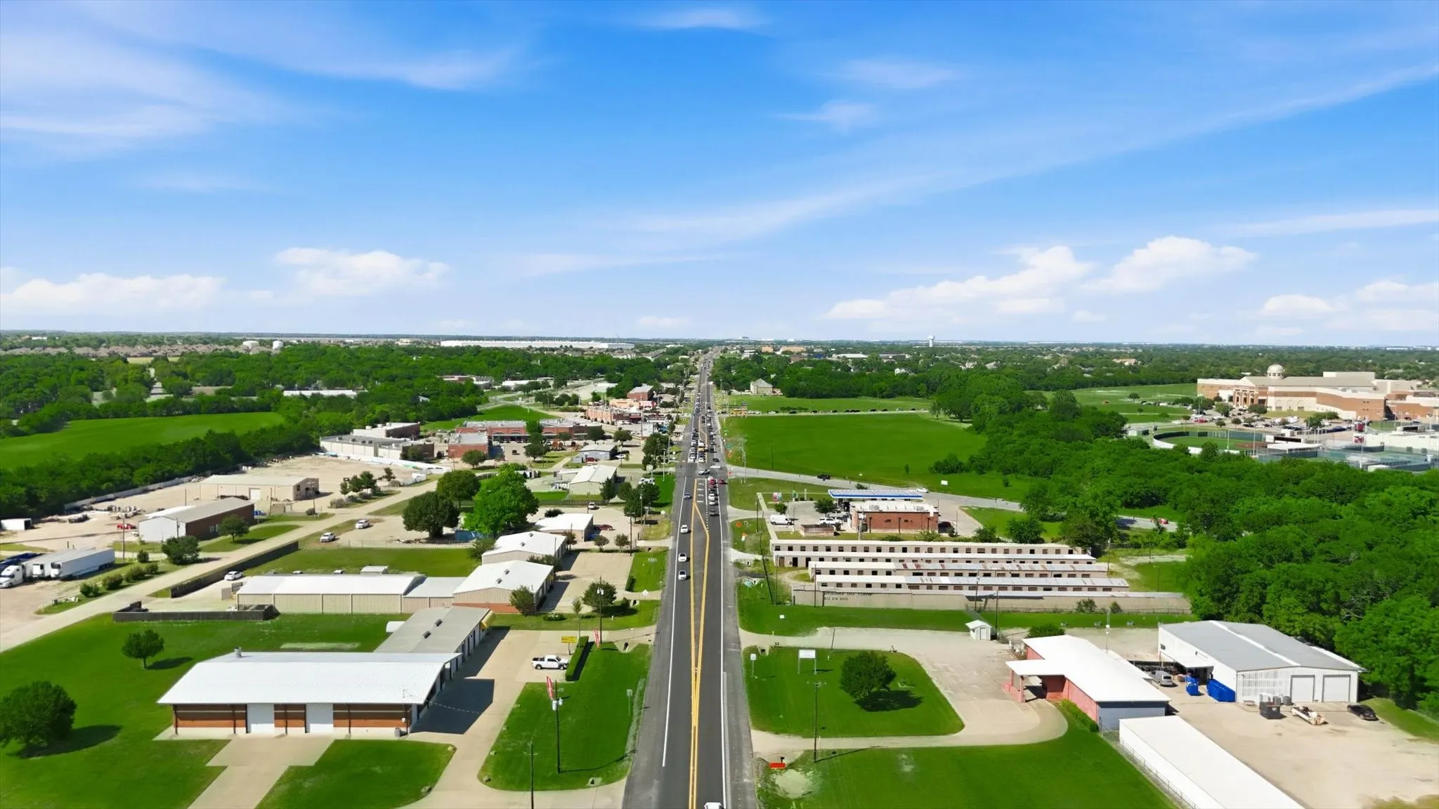 Expansive aerial perspective showcasing a commercial district with a broad, paved thoroughfare