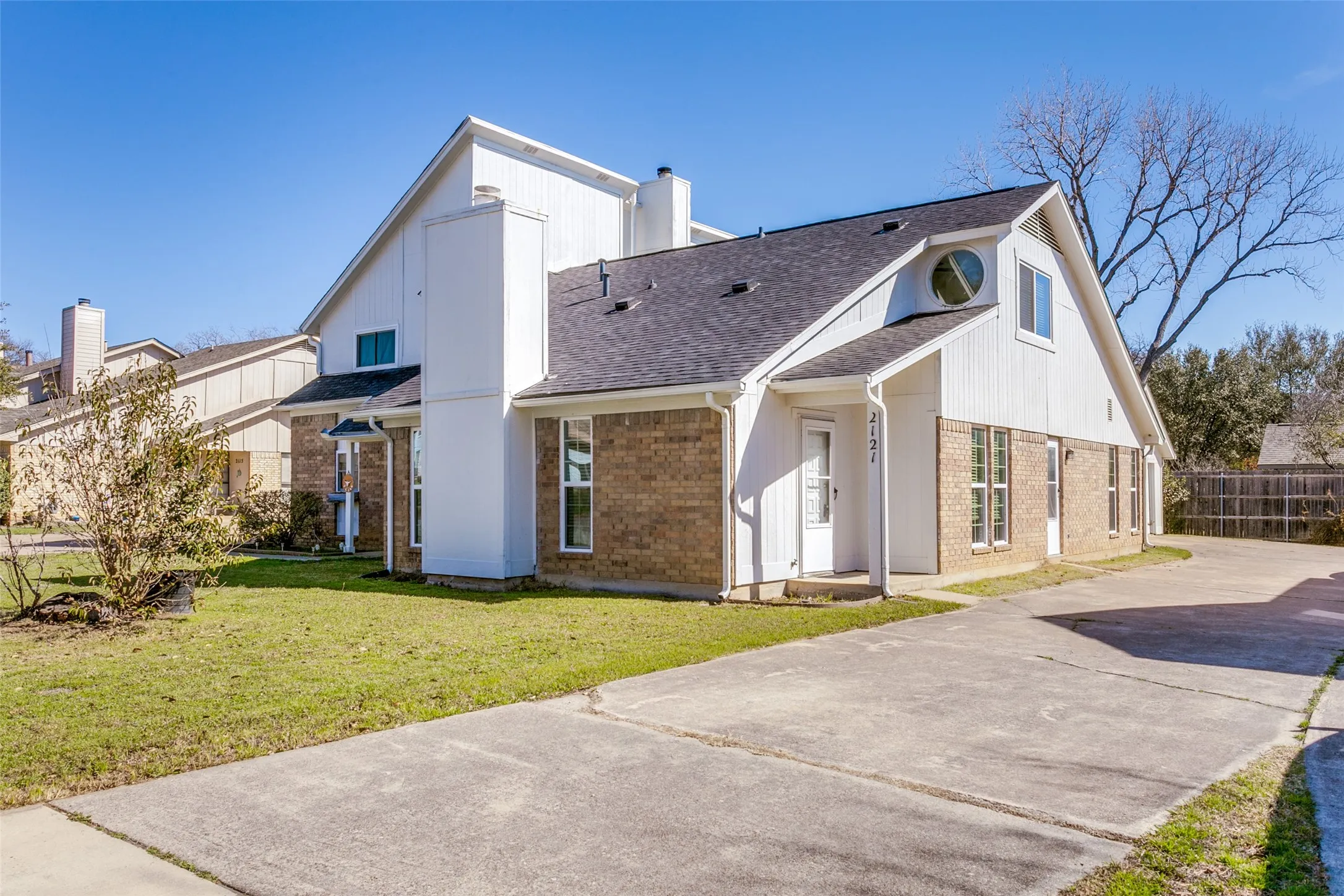 Brick and siding exterior featuring a multi-gable roofline, a prominent circular window, and an extended concrete driveway