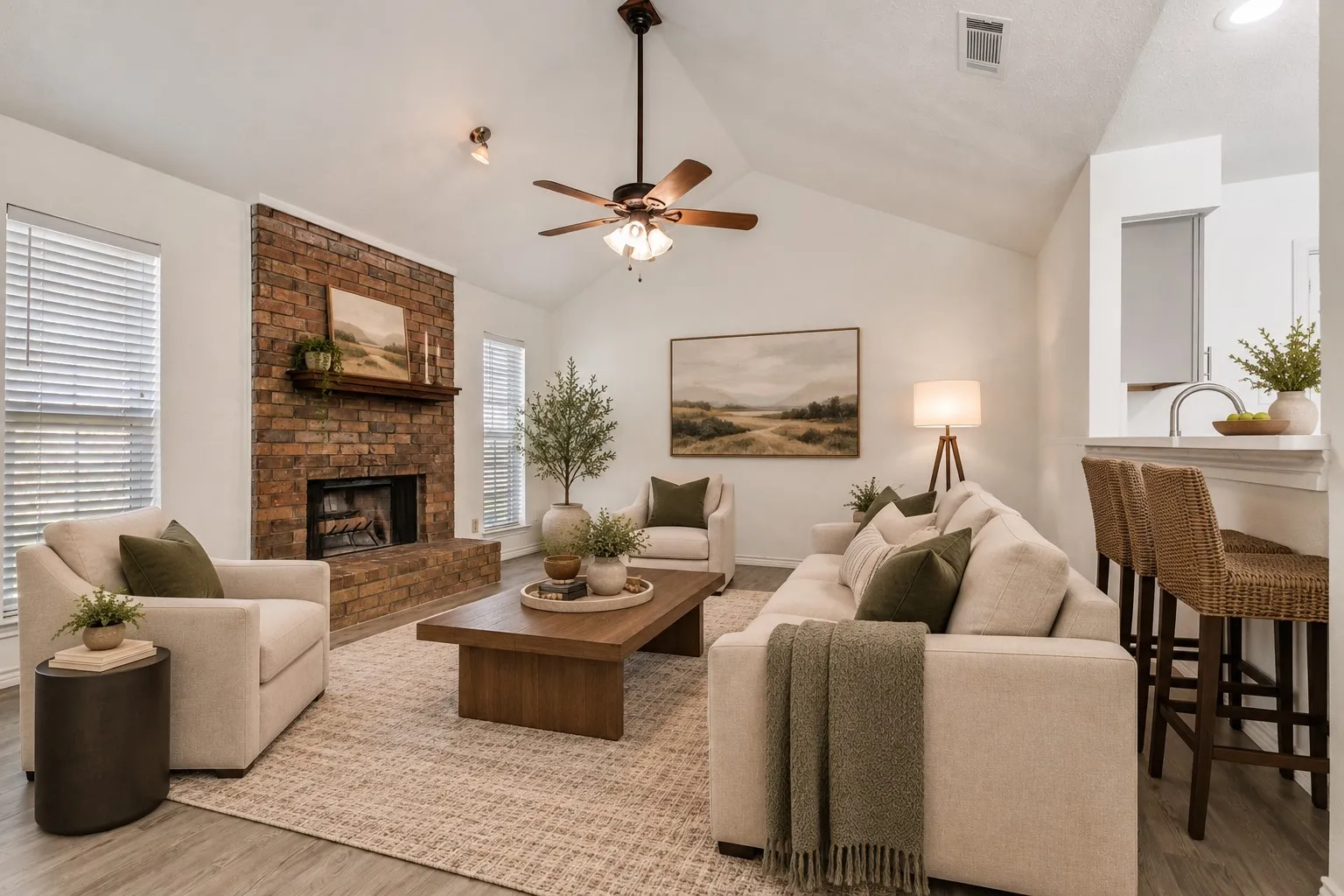 Vaulted ceiling with a ceiling fan, brick fireplace, wood-finish flooring, and white window blinds; virtually staged