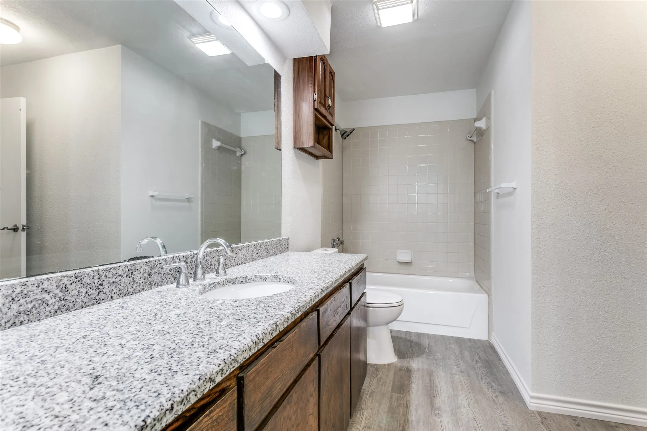 Bathroom featuring a long vanity with a speckled countertop, undermount sink, and dark wood-finish cabinetry