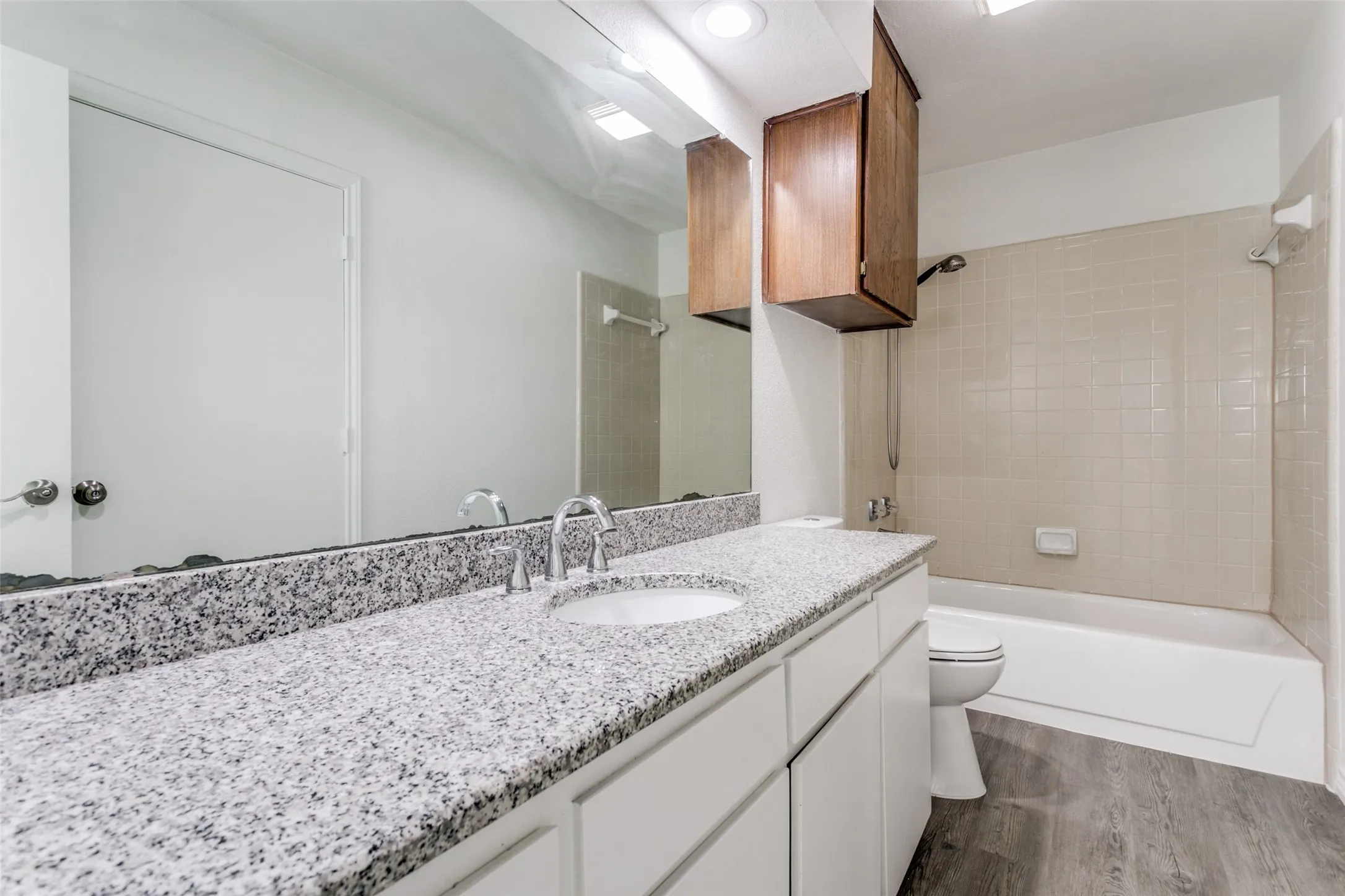 Upstairs bathroom with granite countertop, undermount sinks, chrome fixtures, and wood-finish cabinetry