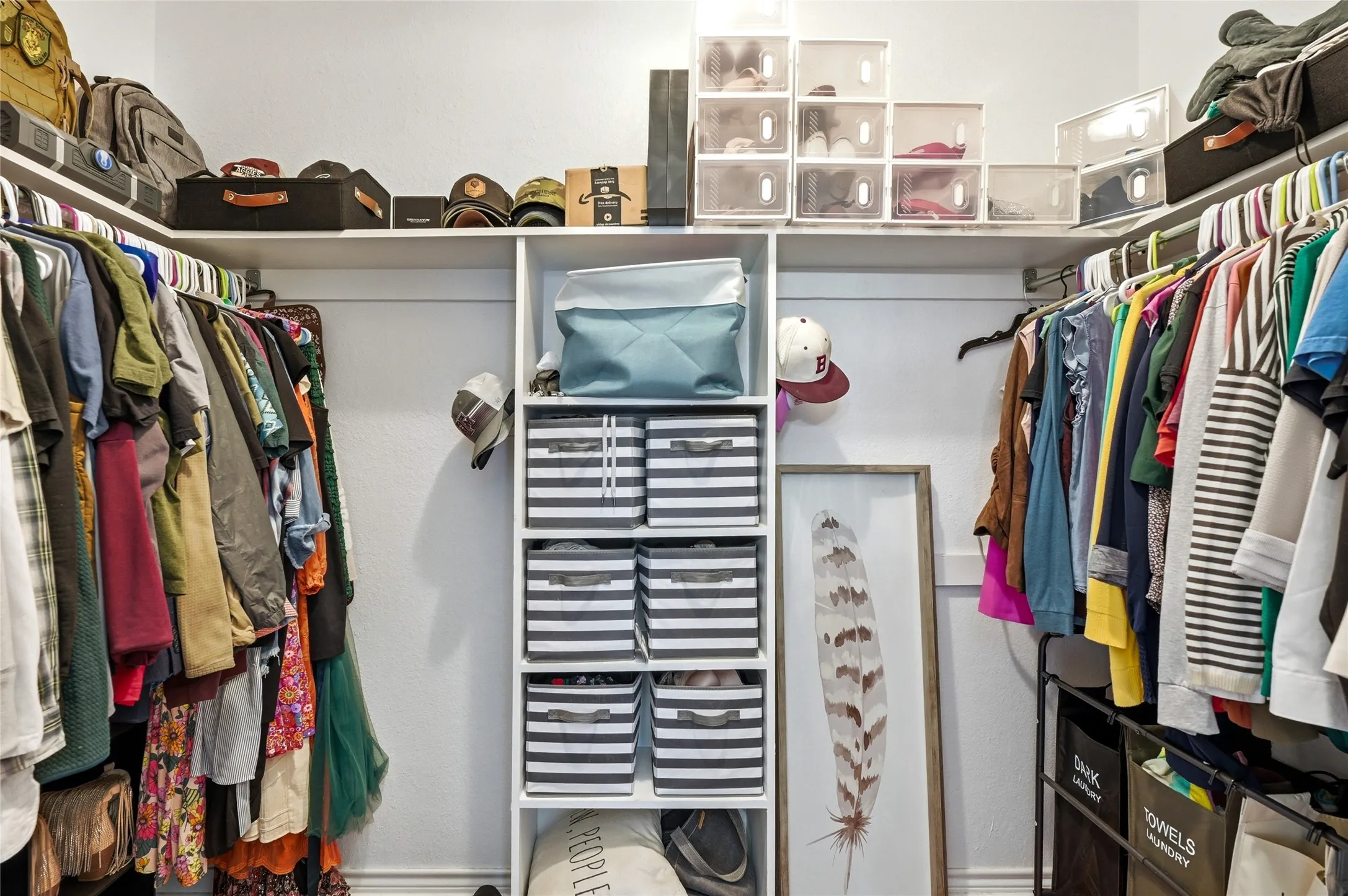 Built-in closet system featuring white shelving, multiple hanging rods, and integrated vertical storage compartments