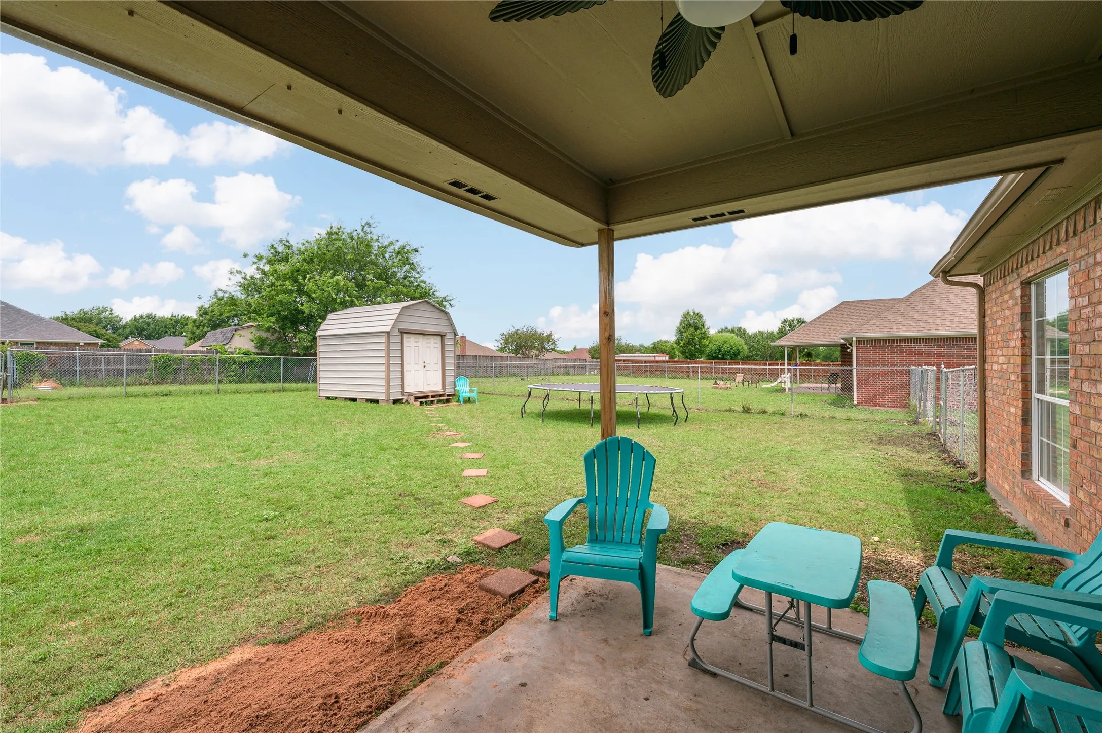 Covered patio with a ceiling fan, concrete flooring, and an expansive grassy yard