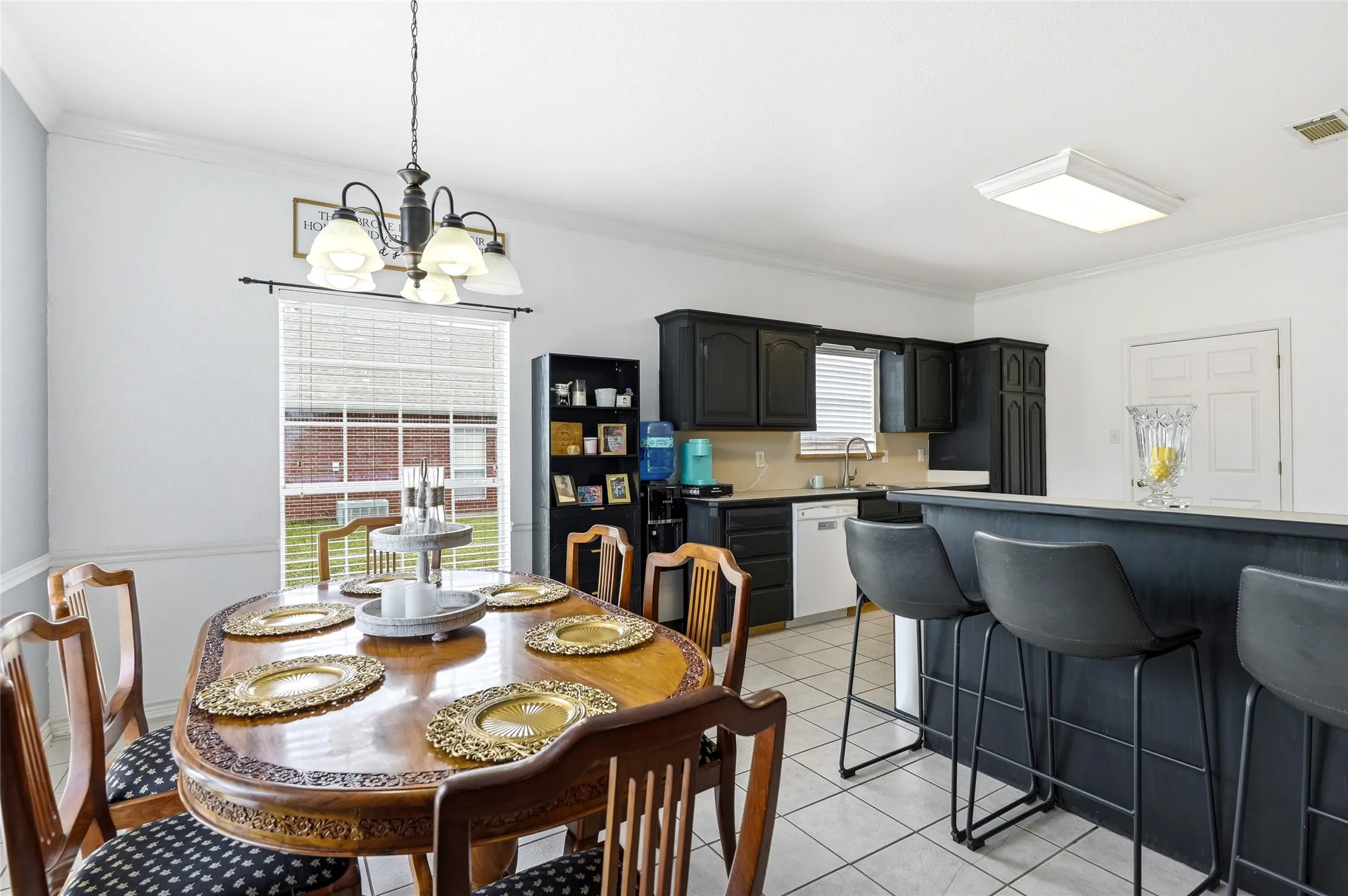 Open-concept kitchen and dining area featuring a breakfast bar with seating, dark wood-finish cabinetry, light-toned countertops, and a tile floor