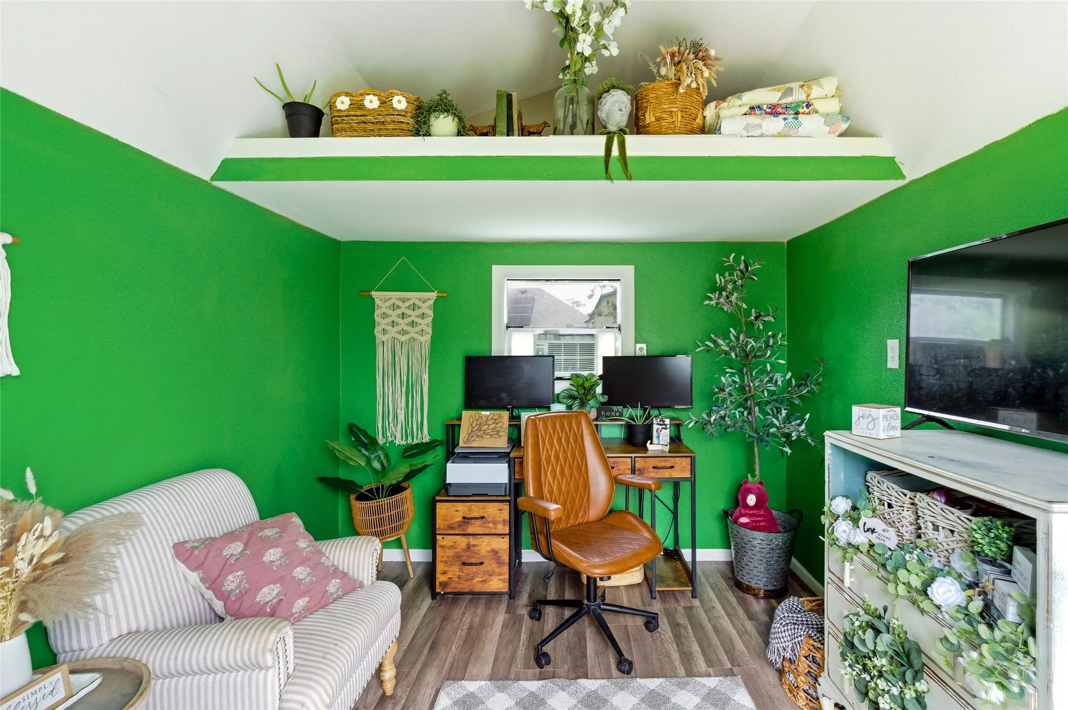 Brightly painted interior room featuring wood-finish flooring, a built-in upper shelf, and a window with white trim