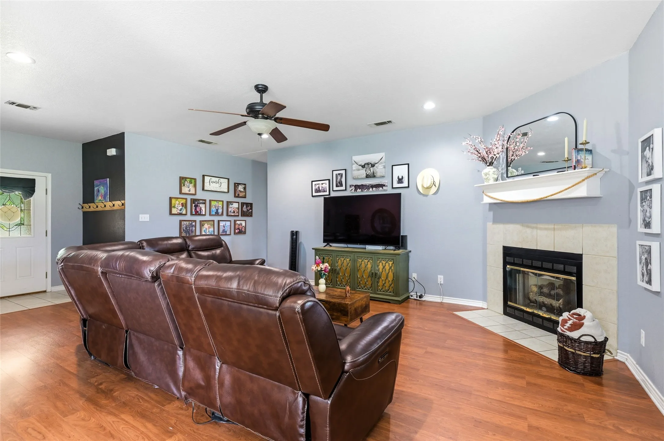 Spacious living area featuring wood-finish flooring, a ceiling fan with integrated lighting, and recessed lighting