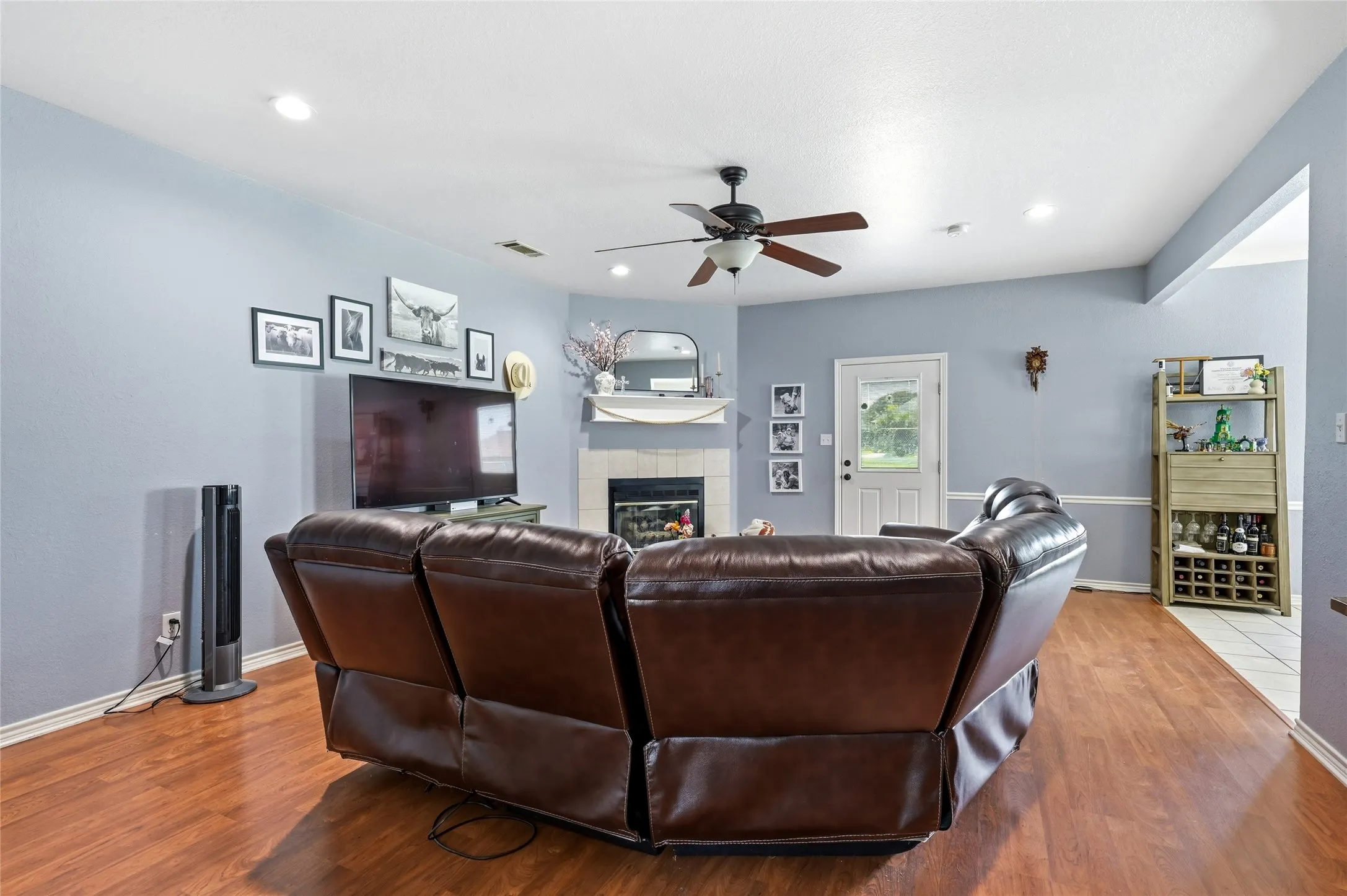 Living area featuring wood-finish flooring, a ceiling fan with light fixture, recessed lighting, and a fireplace with a mantel