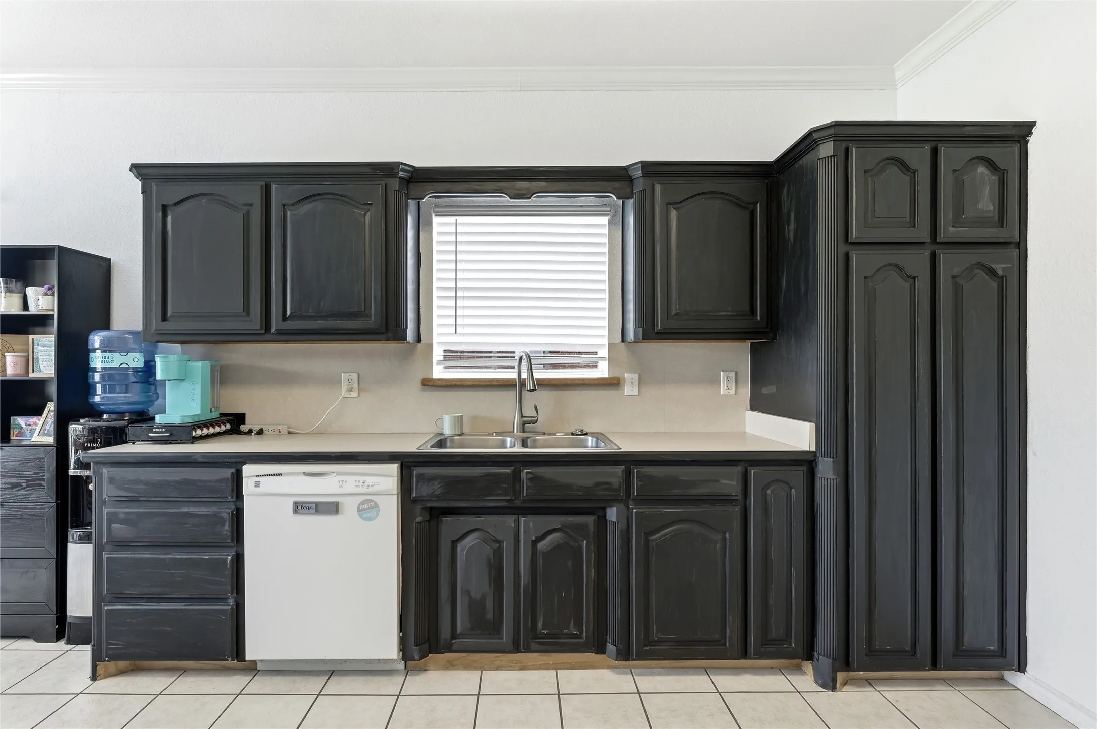 Kitchen featuring dark wood-finish cabinetry, light-toned countertops, and a stainless steel sink with a gooseneck faucet