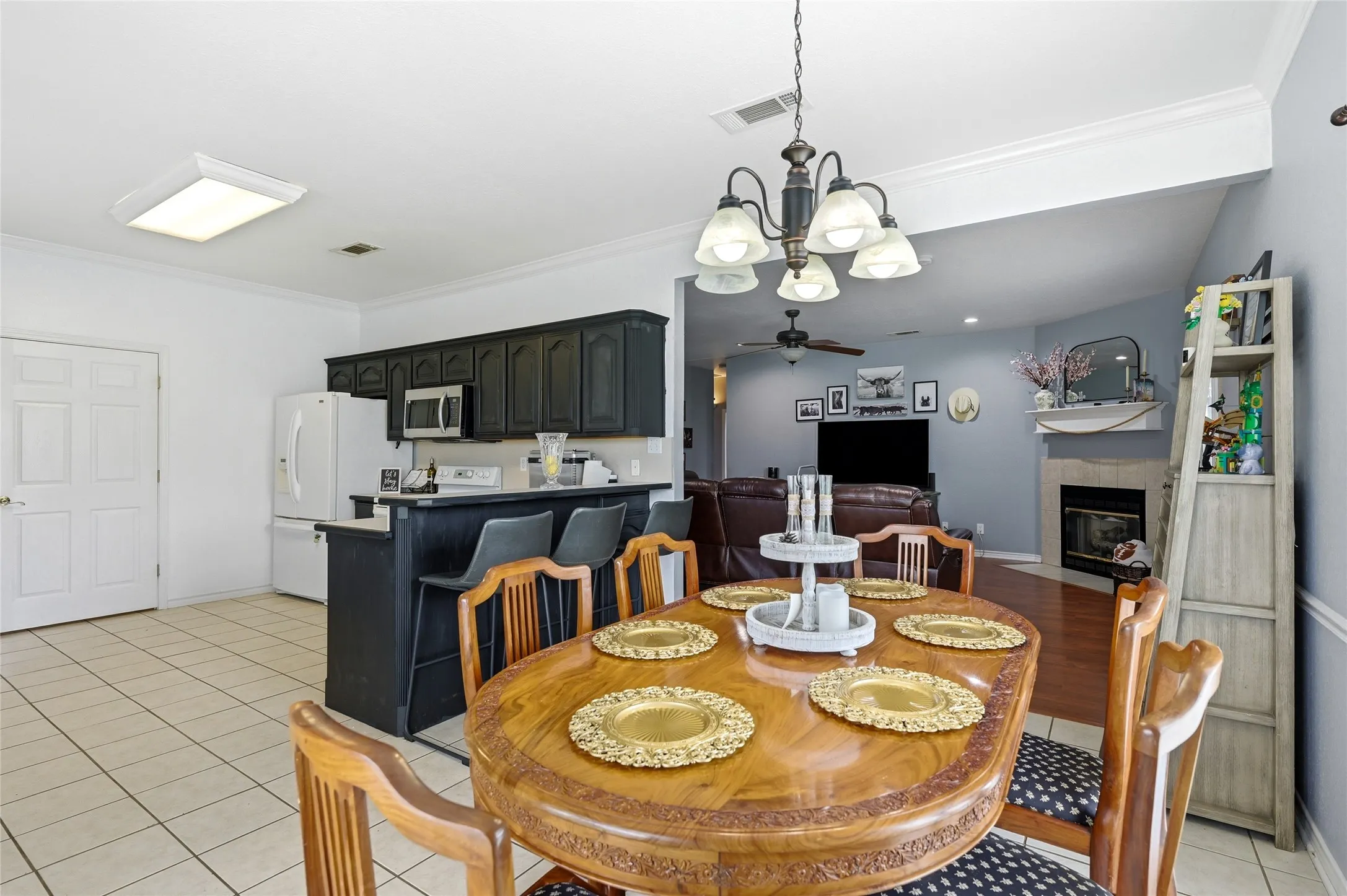 Open-concept dining area featuring a wood-finish table, chandelier lighting, and tile flooring