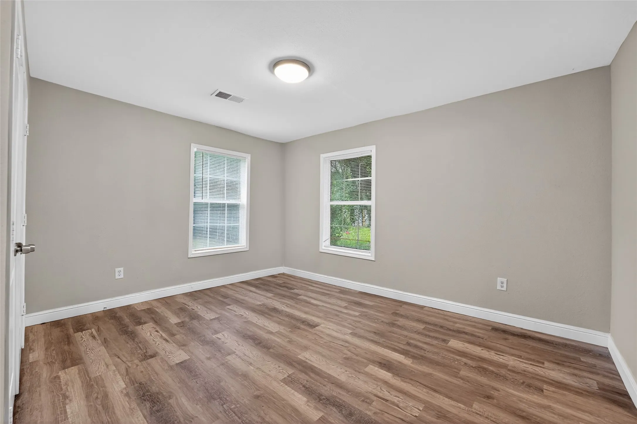 Room featuring wood-finish flooring, light gray wall paint, and white trim