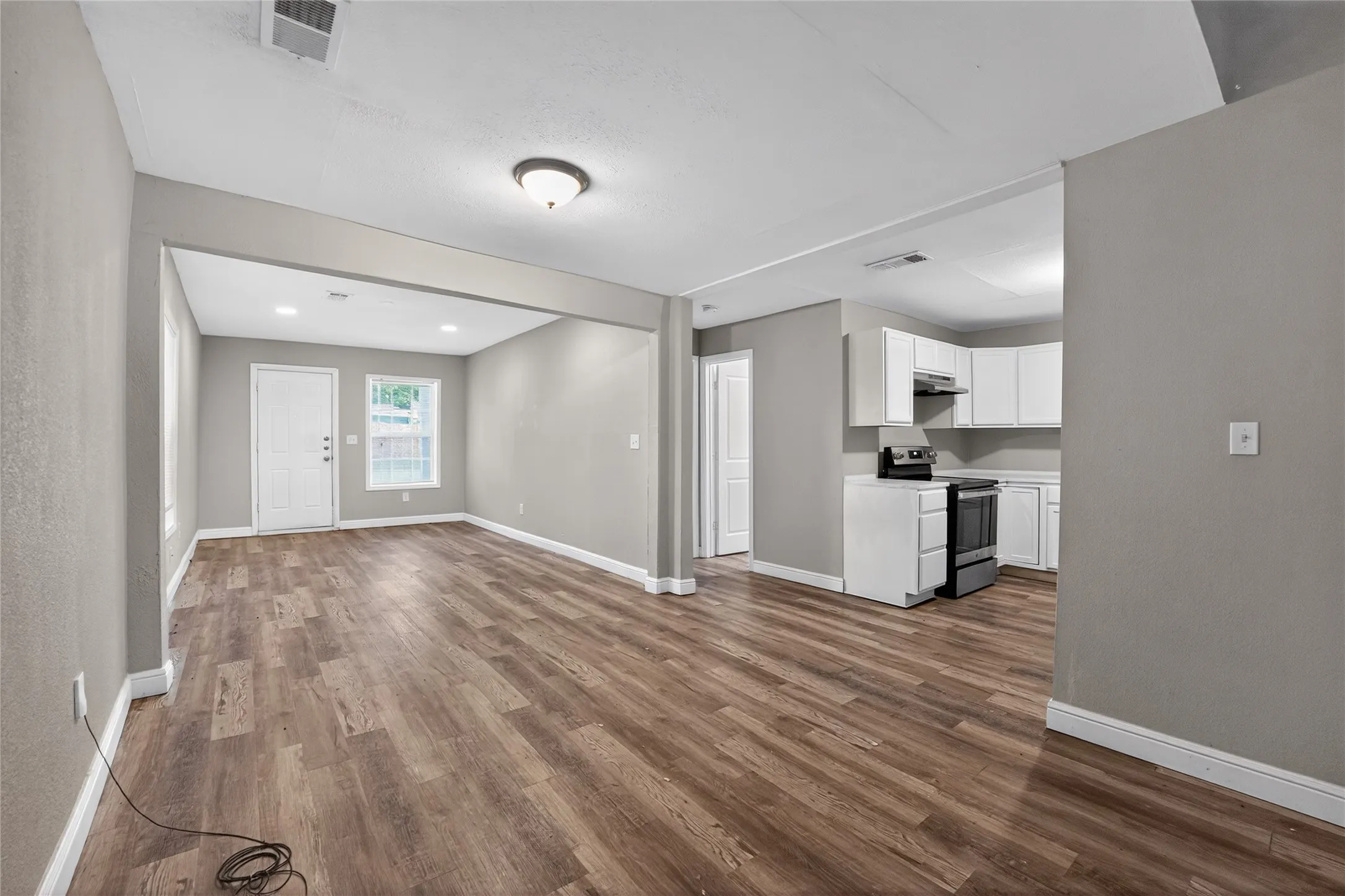 Open-concept living area with wood-finish flooring, neutral gray walls, and white baseboards
