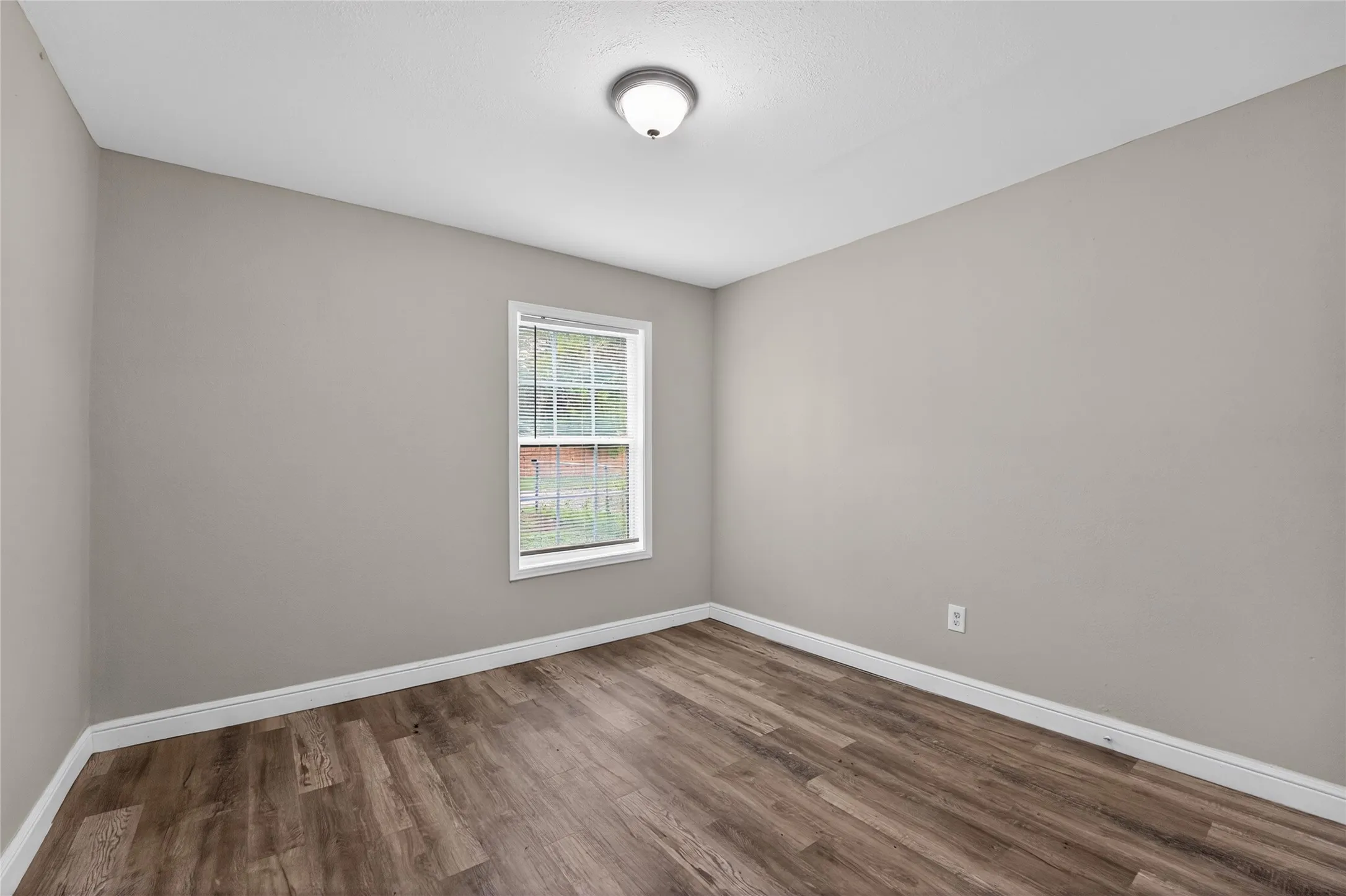 Room featuring wood-finish flooring, neutral wall paint, and white trim