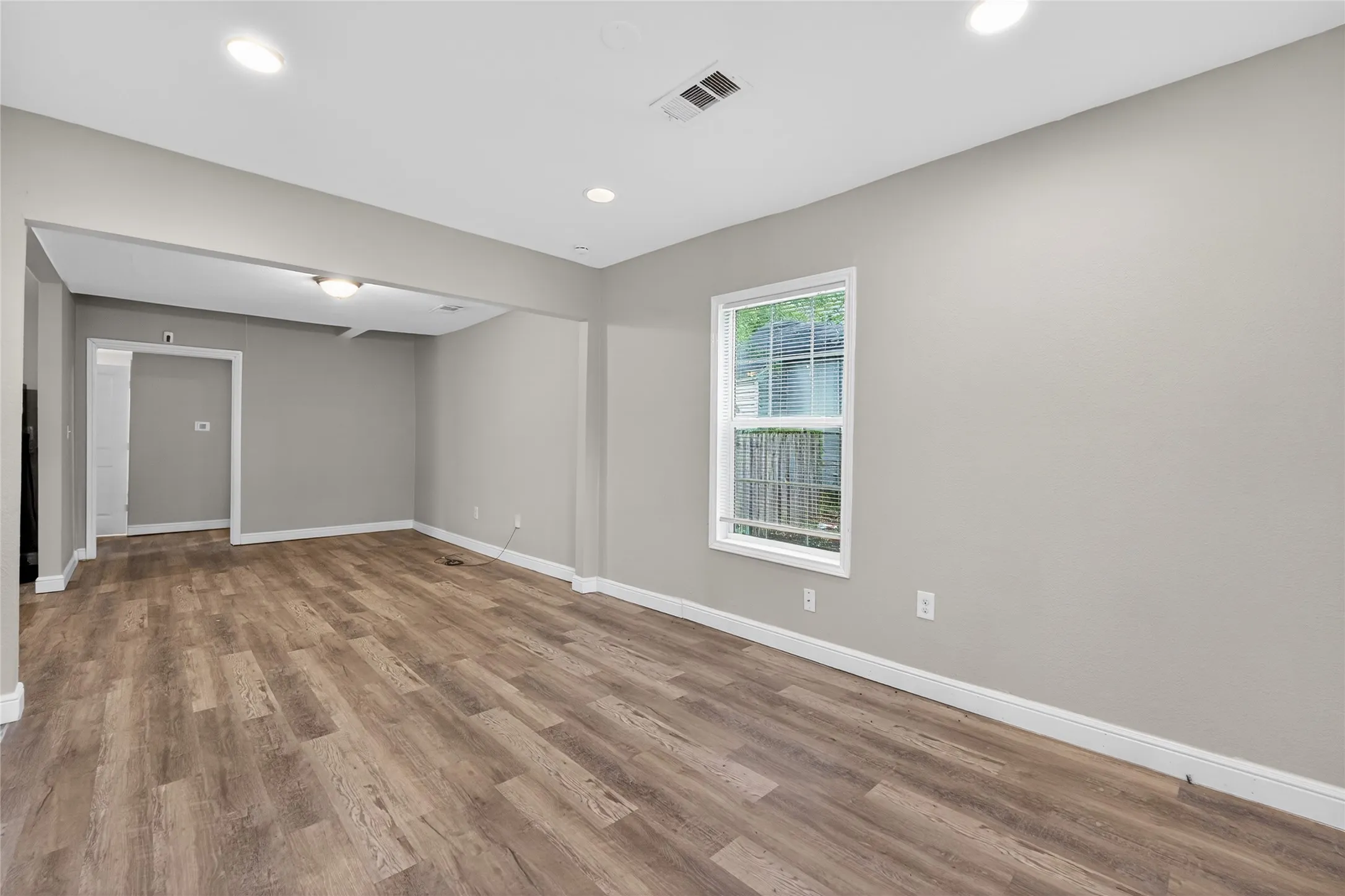 Spacious room featuring wood-finish flooring, recessed lighting, and a neutral color palette