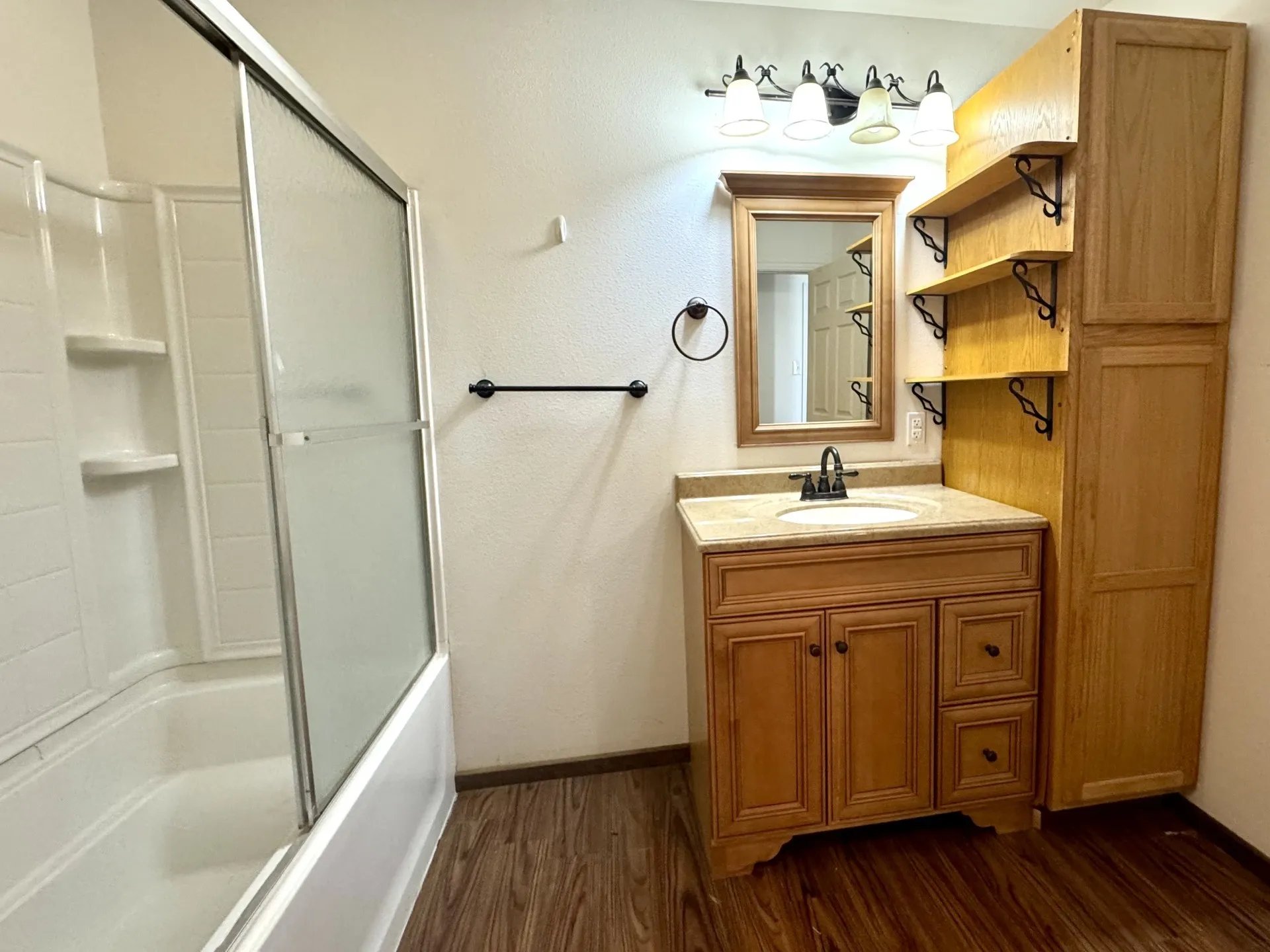 FULL Hall Bathroom featuring a wood-finish vanity with a single basin sink and stone-finish countertop