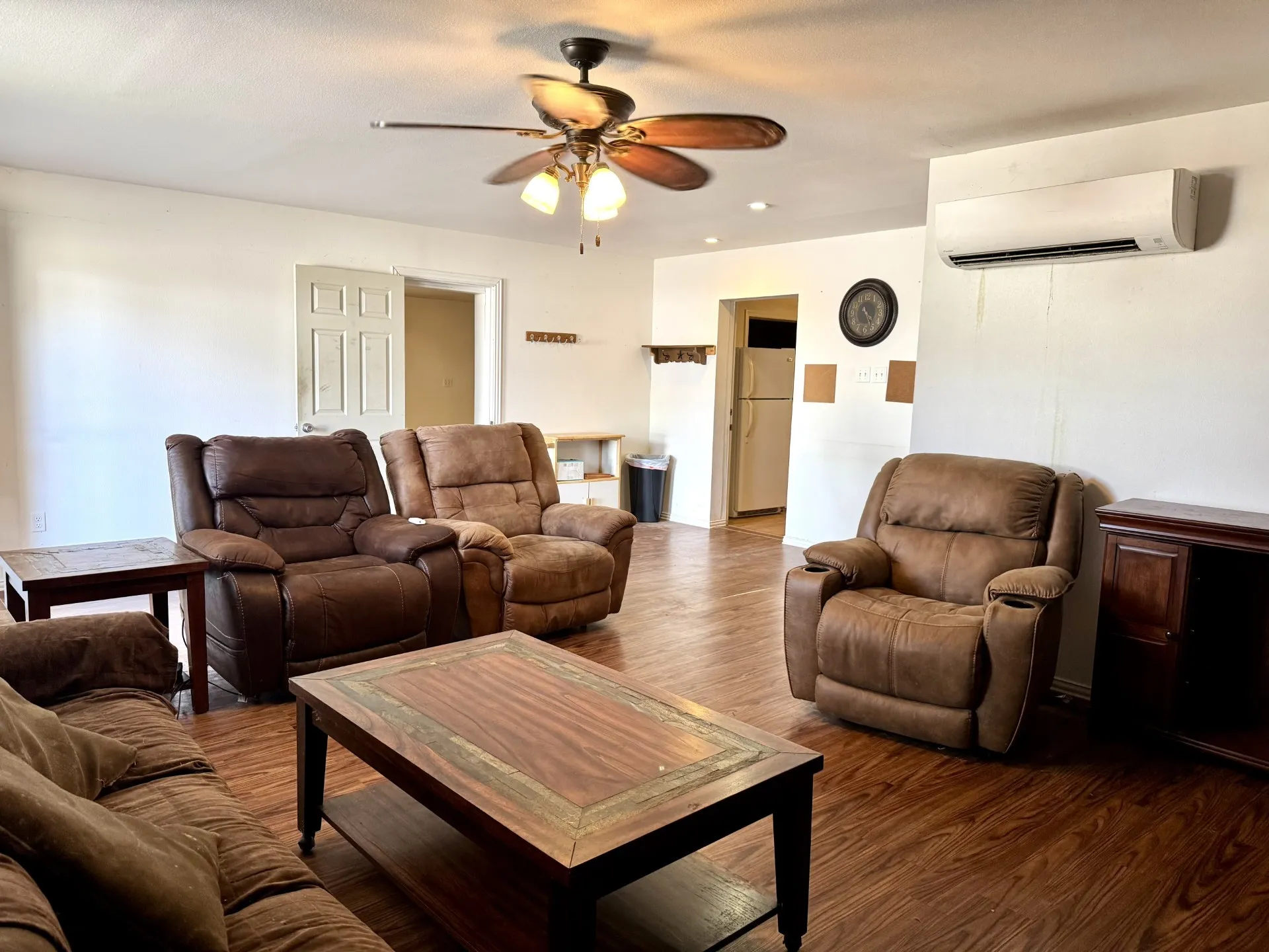 Spacious Front Living Room featuring wood-finish flooring, a ceiling fan with integrated lighting, and a wall-mounted Mini-Split Unit