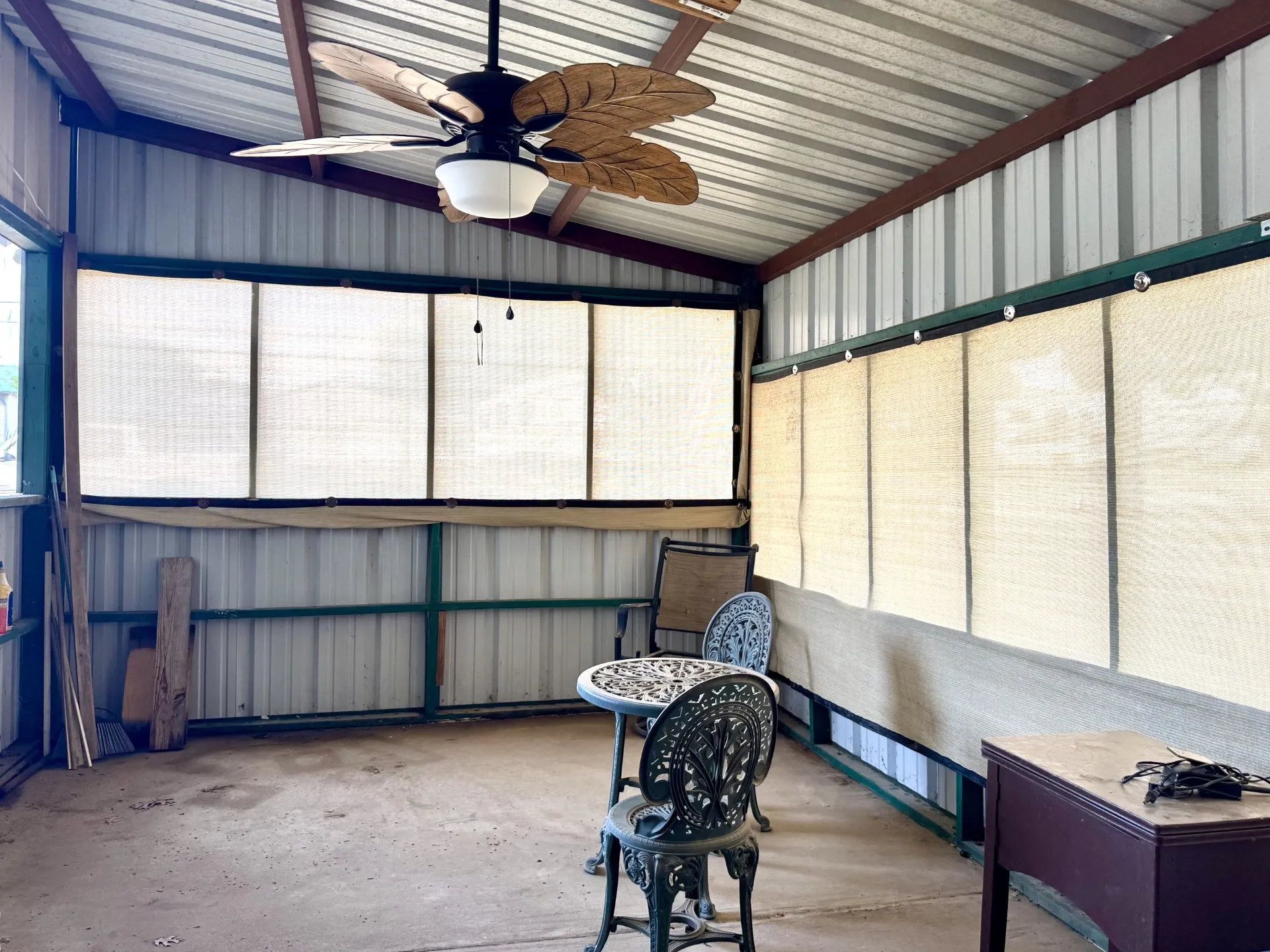 Enclosed Screened Patio Sunroom featuring a corrugated metal roof, a ceiling fan with palm-leaf style blades, and neutral-toned privacy screens