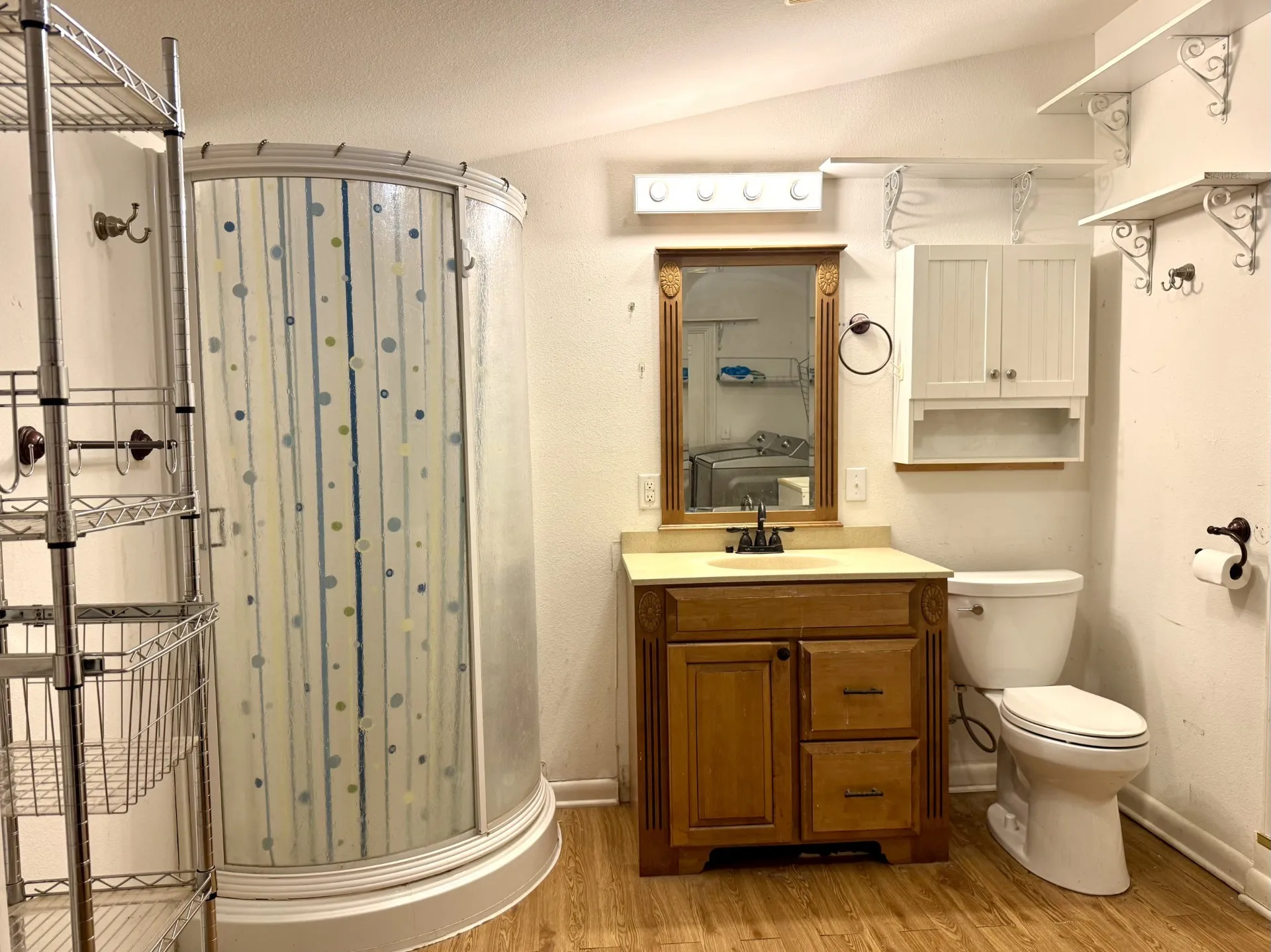Primary Bathroom featuring a corner shower enclosure, wood-finish flooring, and a vanity with a light-colored countertop