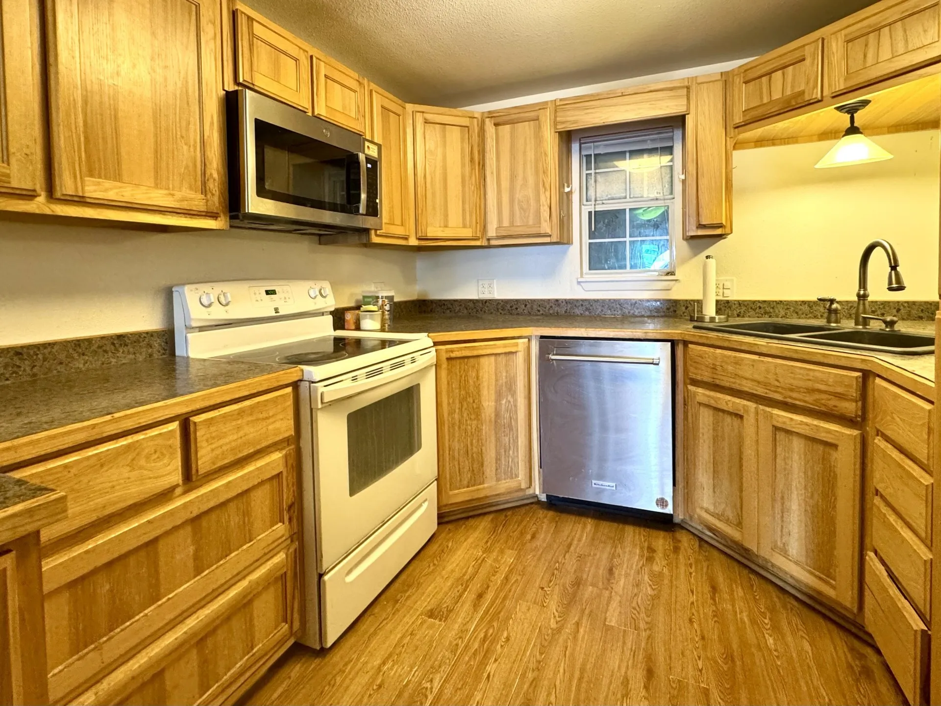 Kitchen featuring wood-finish cabinetry, dark speckled countertops, and wood-finish flooring