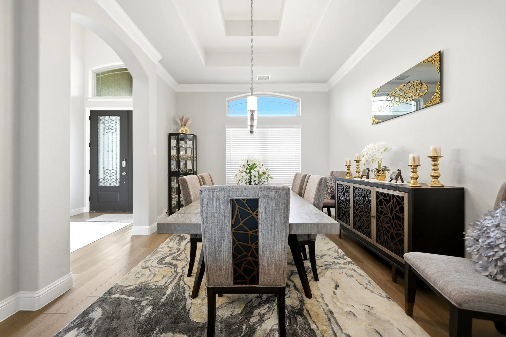 Elegant dining area featuring wood-finish flooring, a tray ceiling with crown molding, and a built-in buffet cabinet with decorative doors