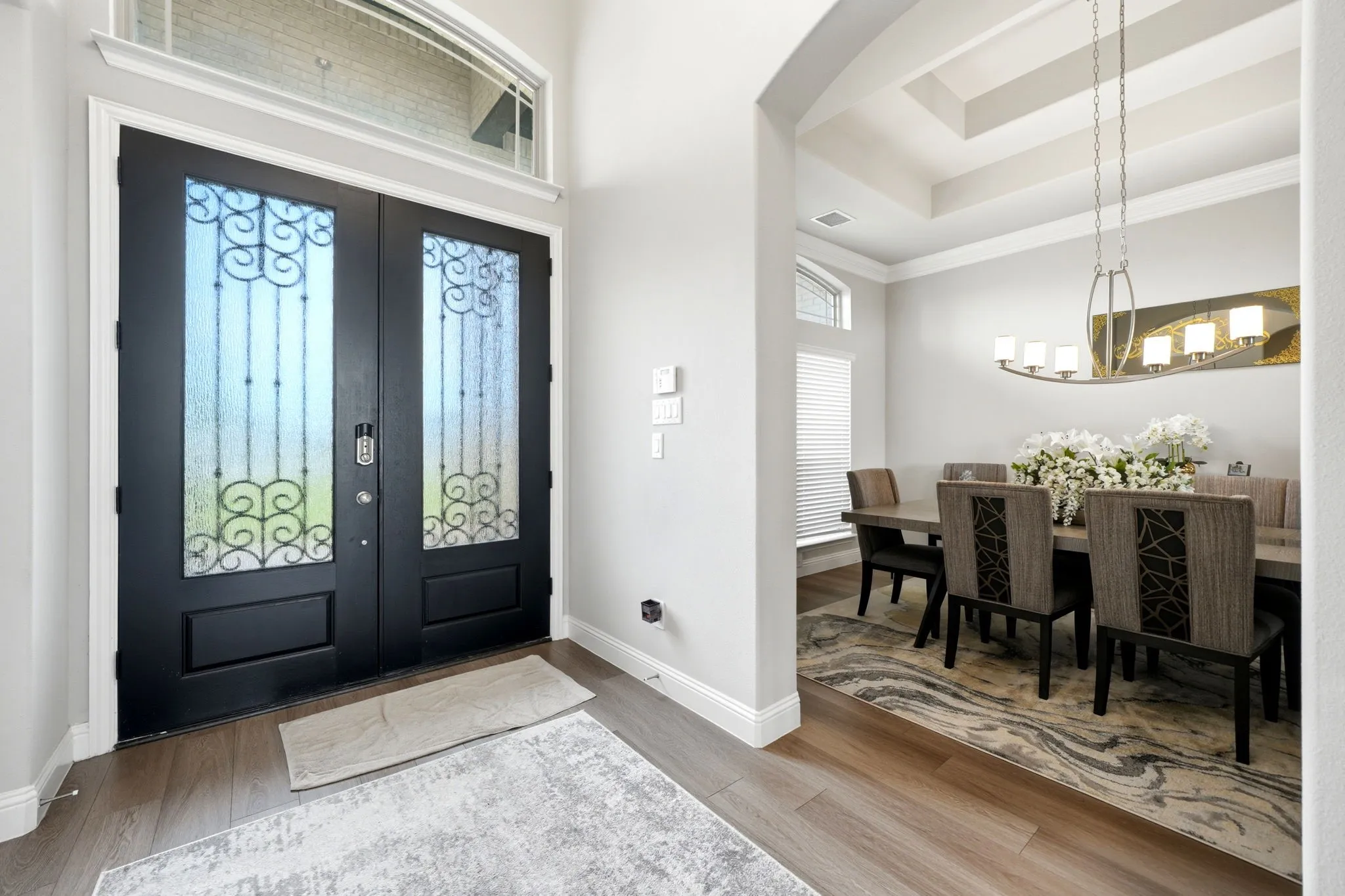 Double entry doors with intricate wrought iron detailing and an arched transom window