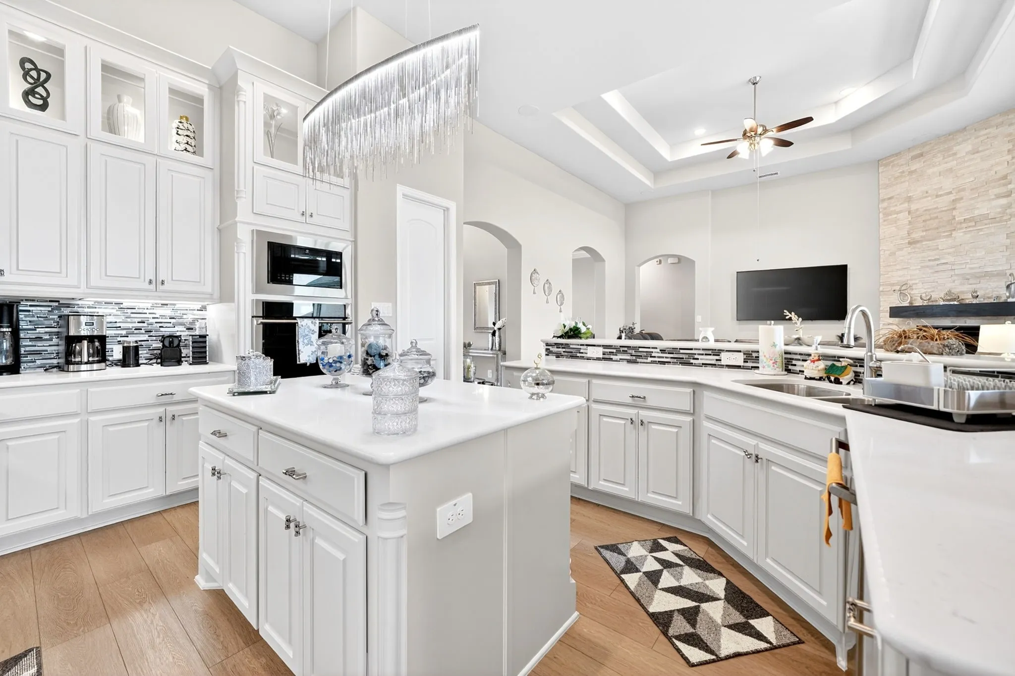 Gourmet kitchen with white cabinetry, built-in stainless steel appliances, a center island, and wood-finish flooring