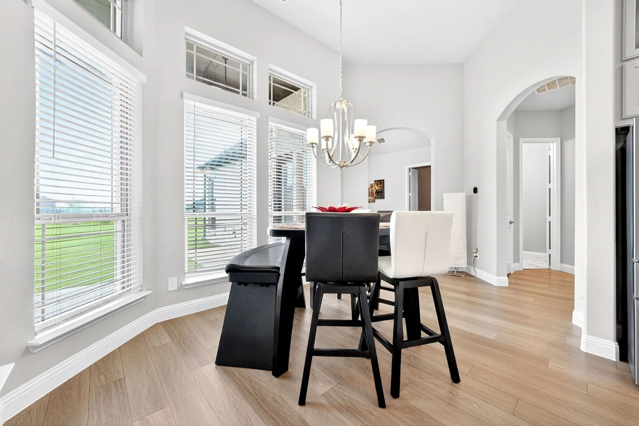Dining area featuring wood-finish flooring, a vaulted ceiling, and multiple windows with horizontal blinds