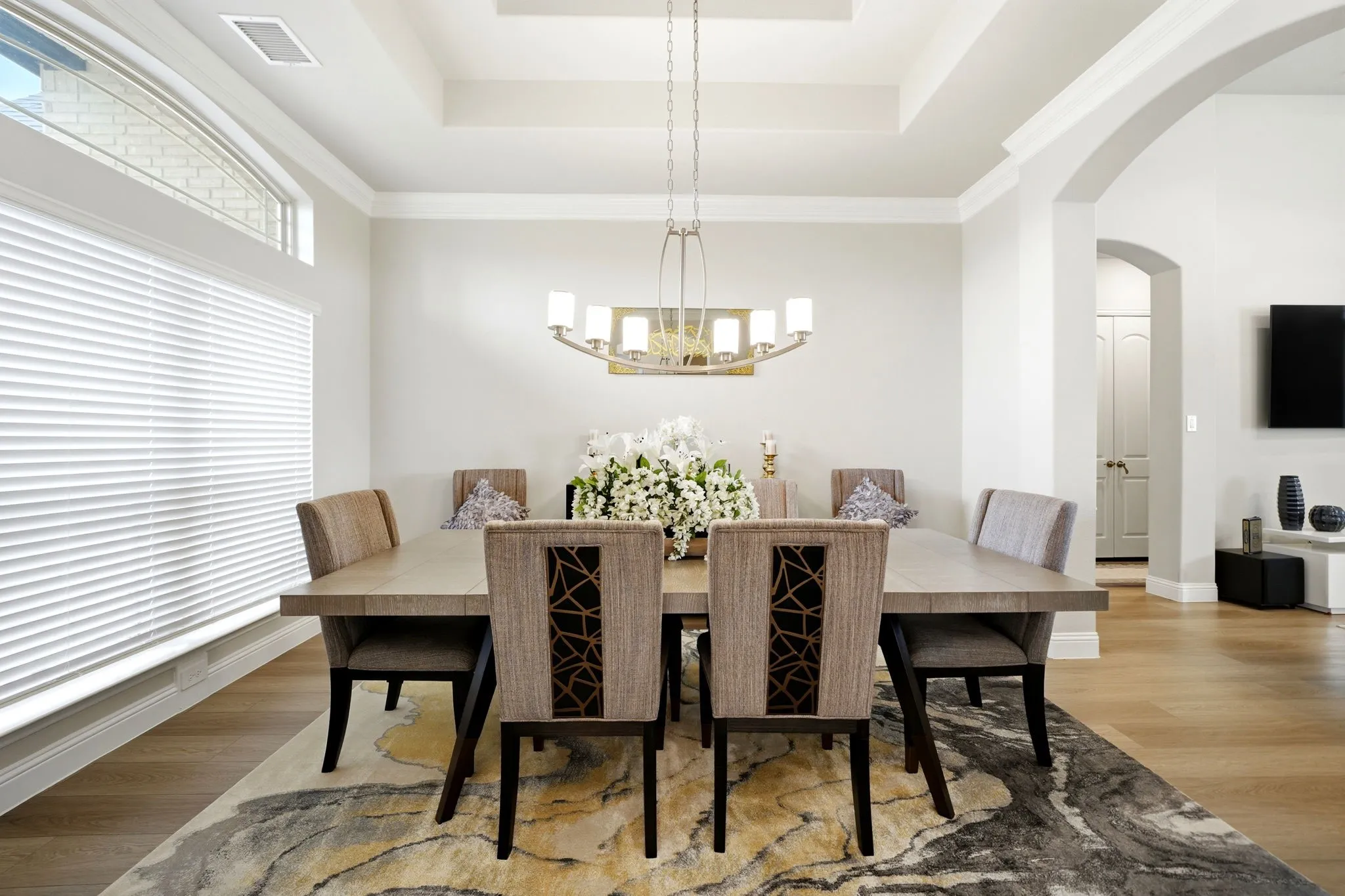 Dining area featuring a coffered ceiling, wood-finish flooring, and an arched doorway