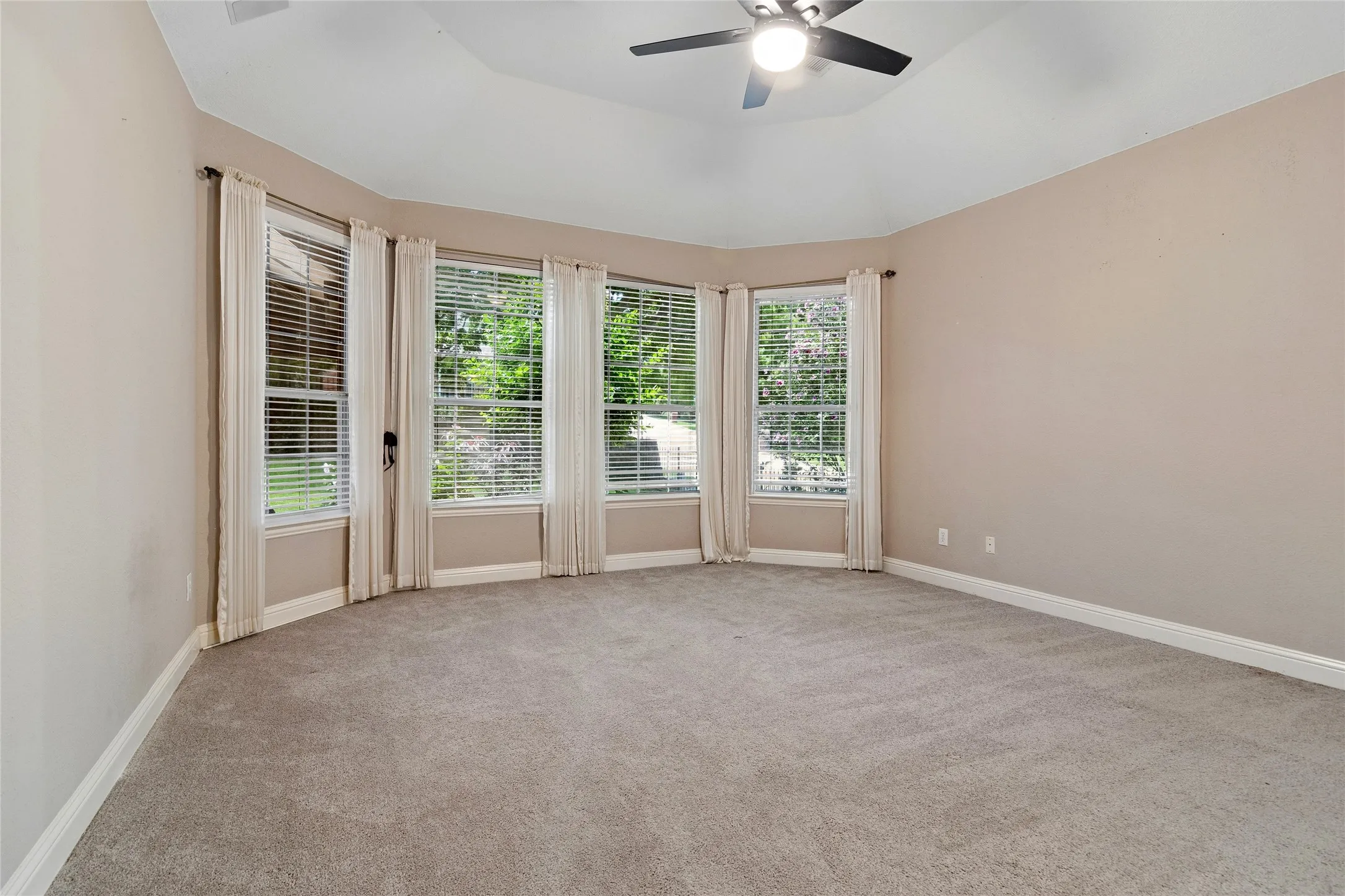 Primary suite, wall of windows viewing backyard, high ceiling and built in speakers