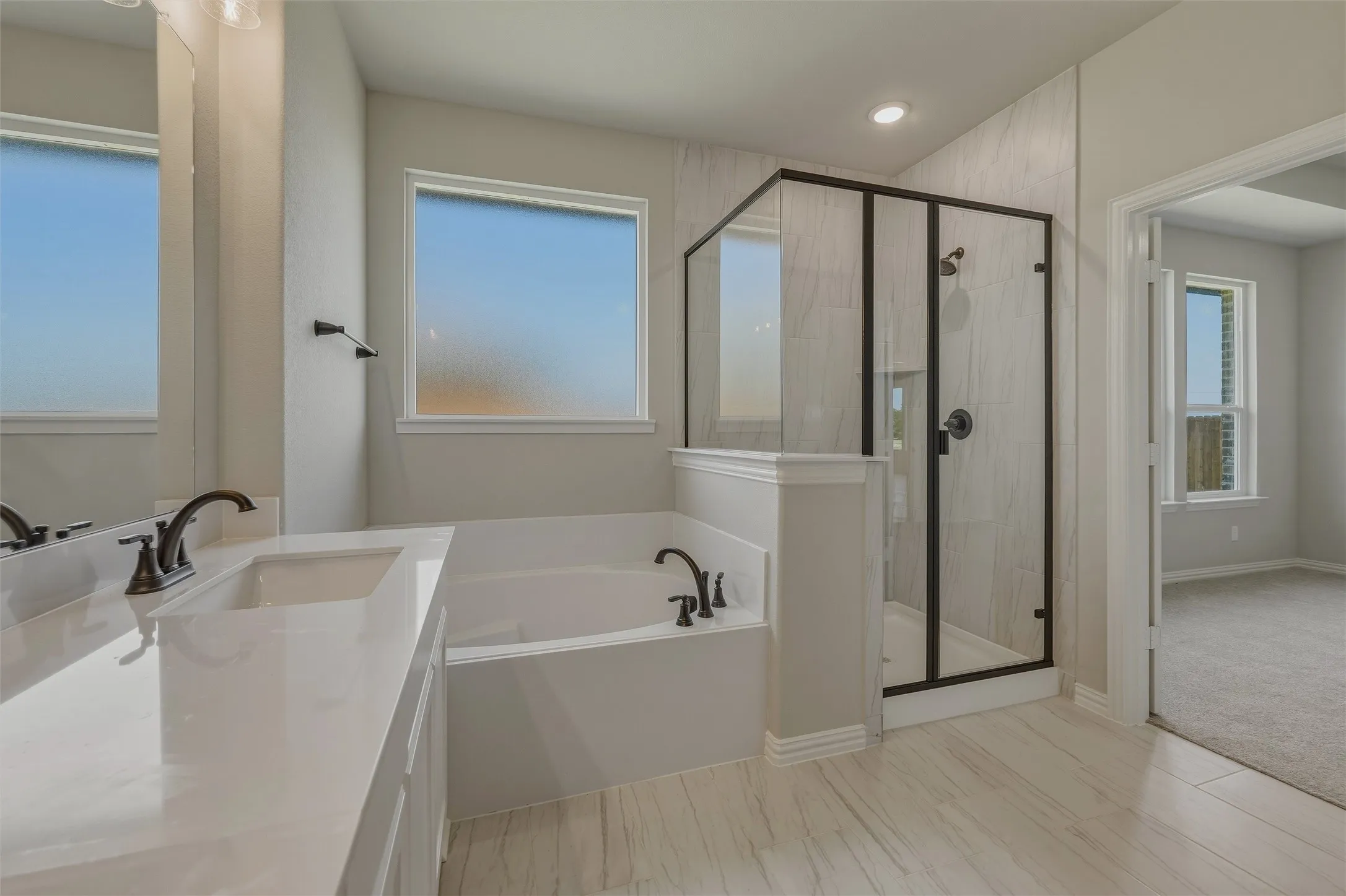 Contemporary bathroom featuring a built-in tub, separate shower with black-framed glass enclosure, and a double vanity with integrated sinks