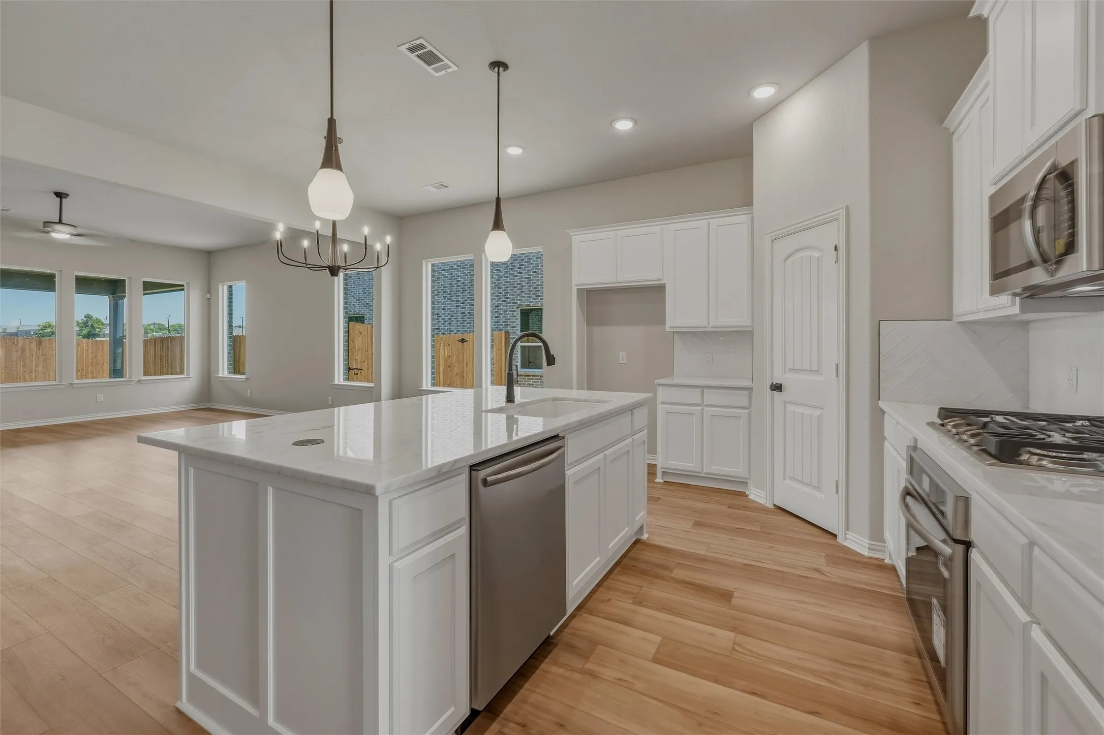 Kitchen featuring a central island with a stone countertop, white shaker cabinetry, stainless steel appliances, and wood-finish flooring