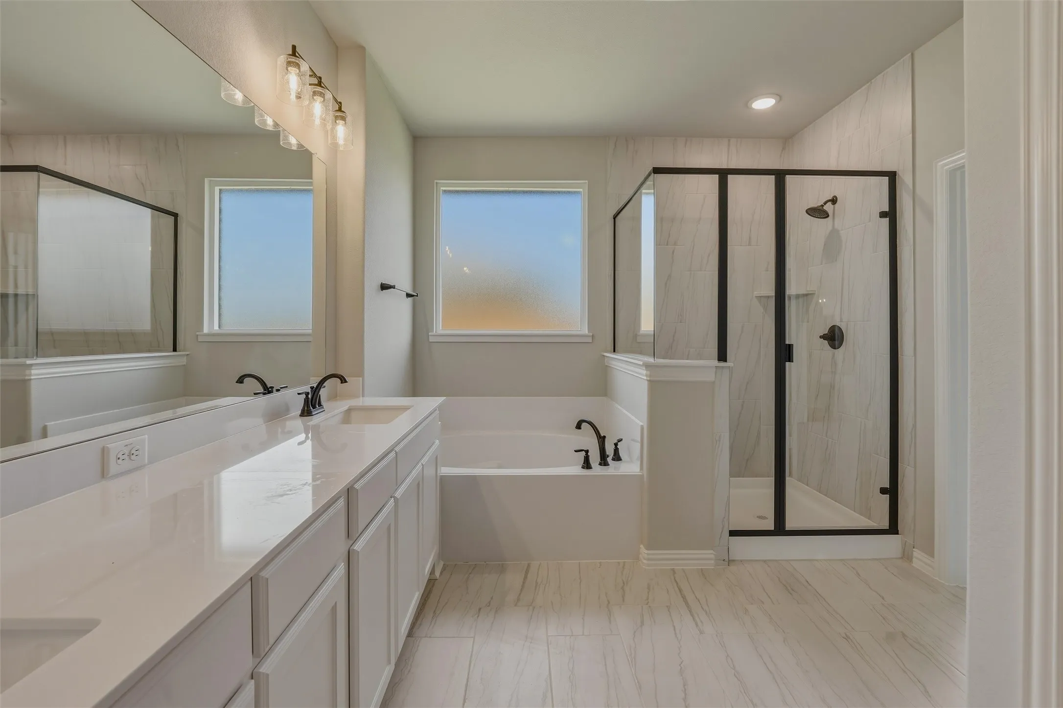 Contemporary bathroom featuring a double vanity with stone-finish countertop, dual undermount sinks, and matte black fixtures