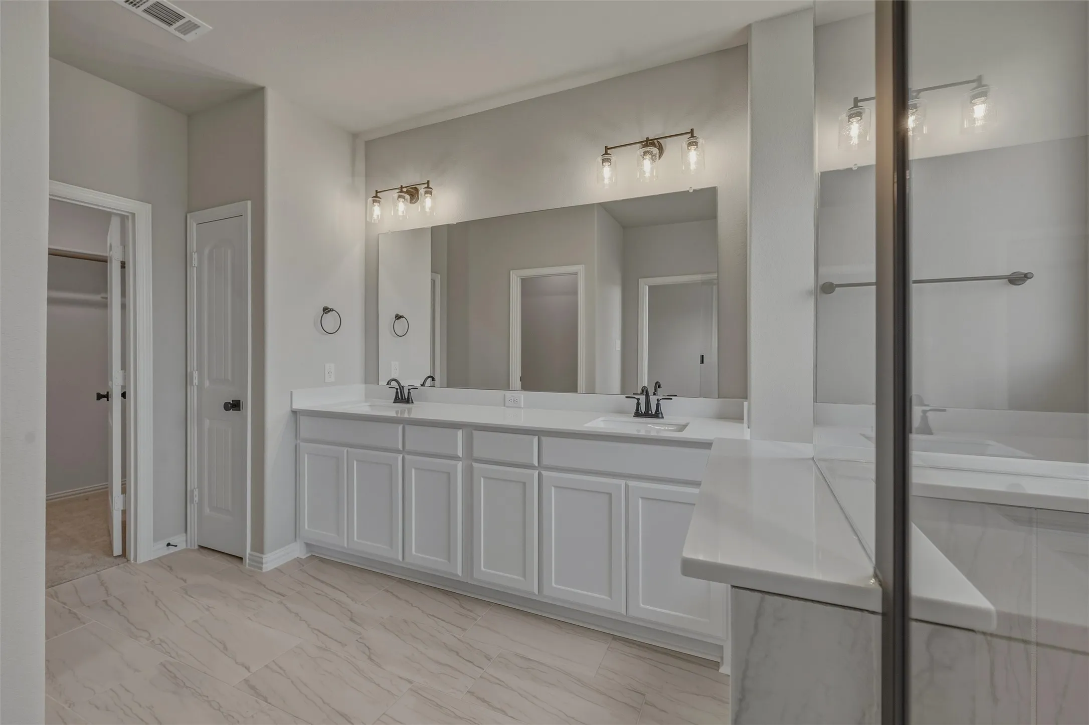 Dual vanity featuring white shaker cabinetry and integrated sinks with black fixtures