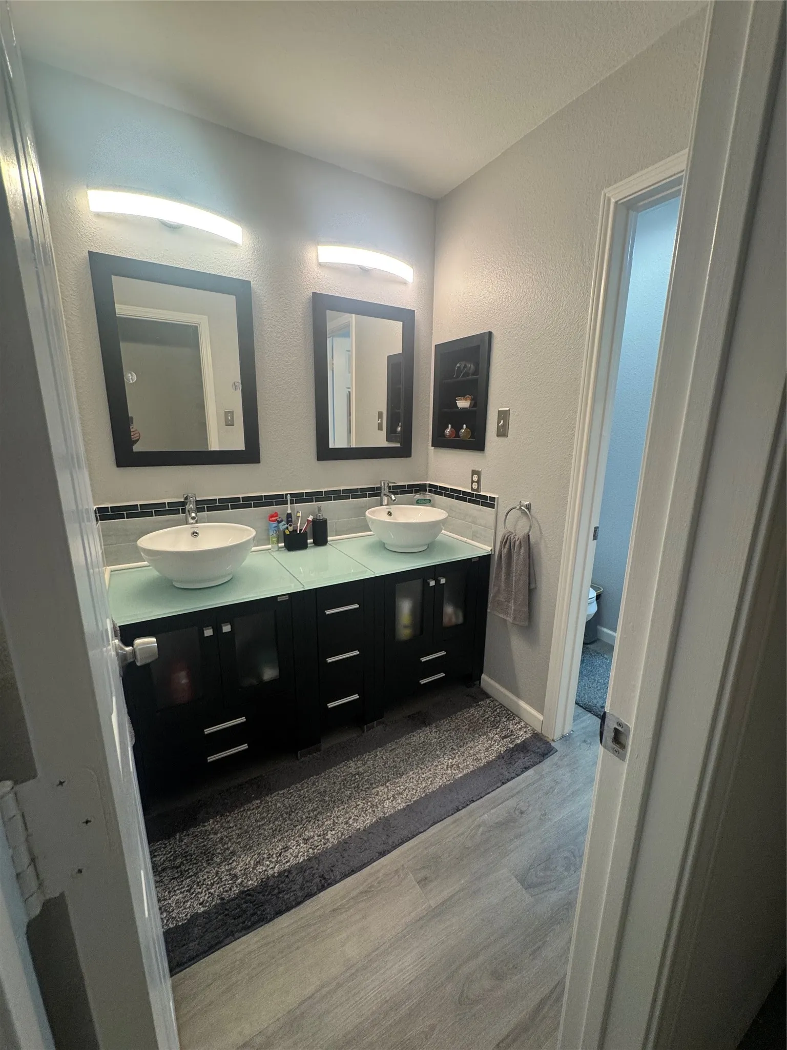 Bathroom featuring a dual vanity with vessel sinks, black cabinetry, and a light blue countertop