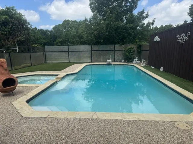 Swimming pool featuring an integrated spa, exposed aggregate concrete decking, and flagstone coping