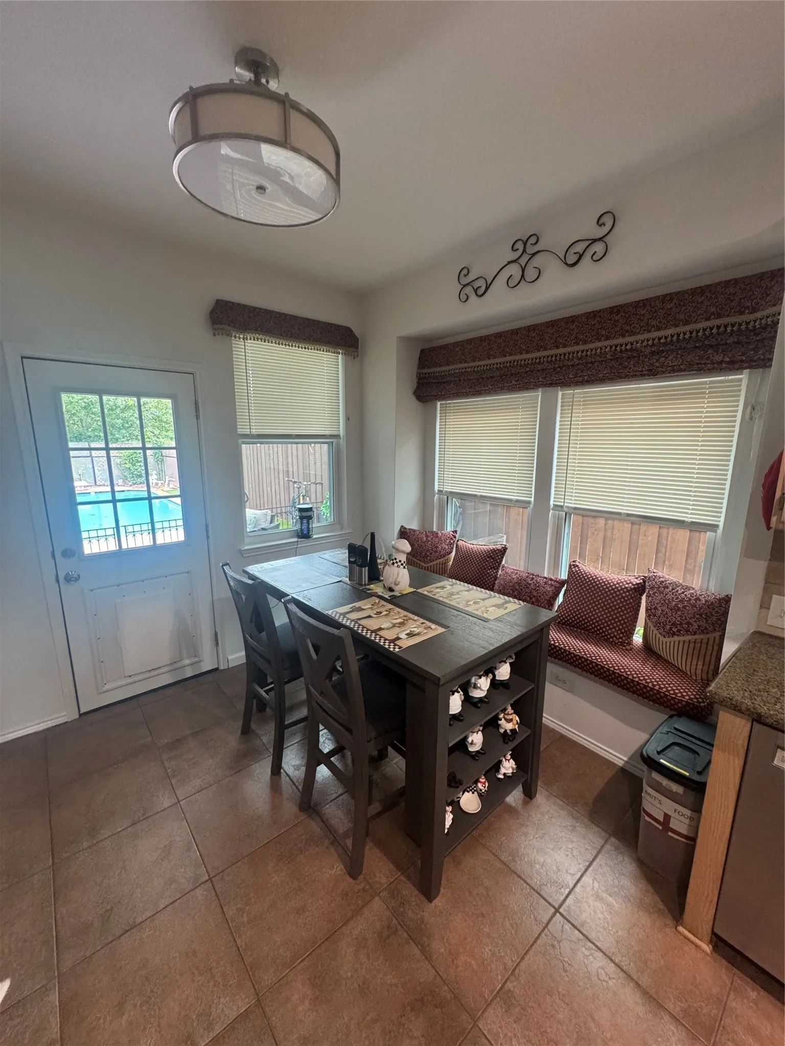 Kitchenette with tile flooring, a built-in window seat, multiple windows with blinds, a white door with glass panels, and a semi-flush mount ceiling light fixture